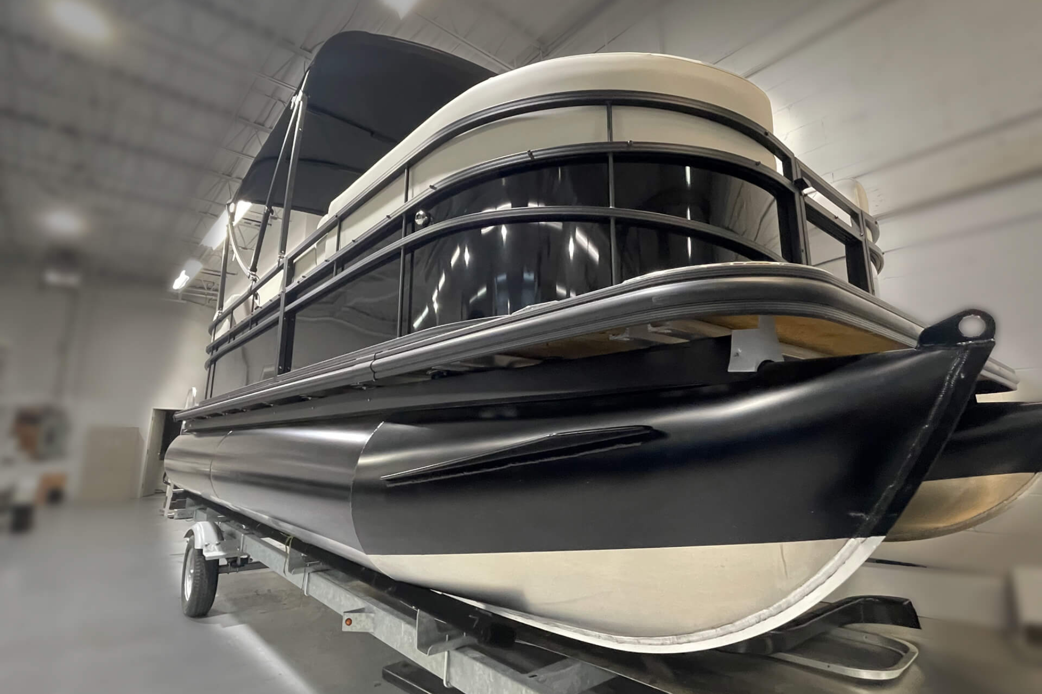 A low front angle view of the 2024 WX Tritoon WX-003, showing the reinforced tritoon hull, aluminum construction, and rail layout that support higher capacity and stability.