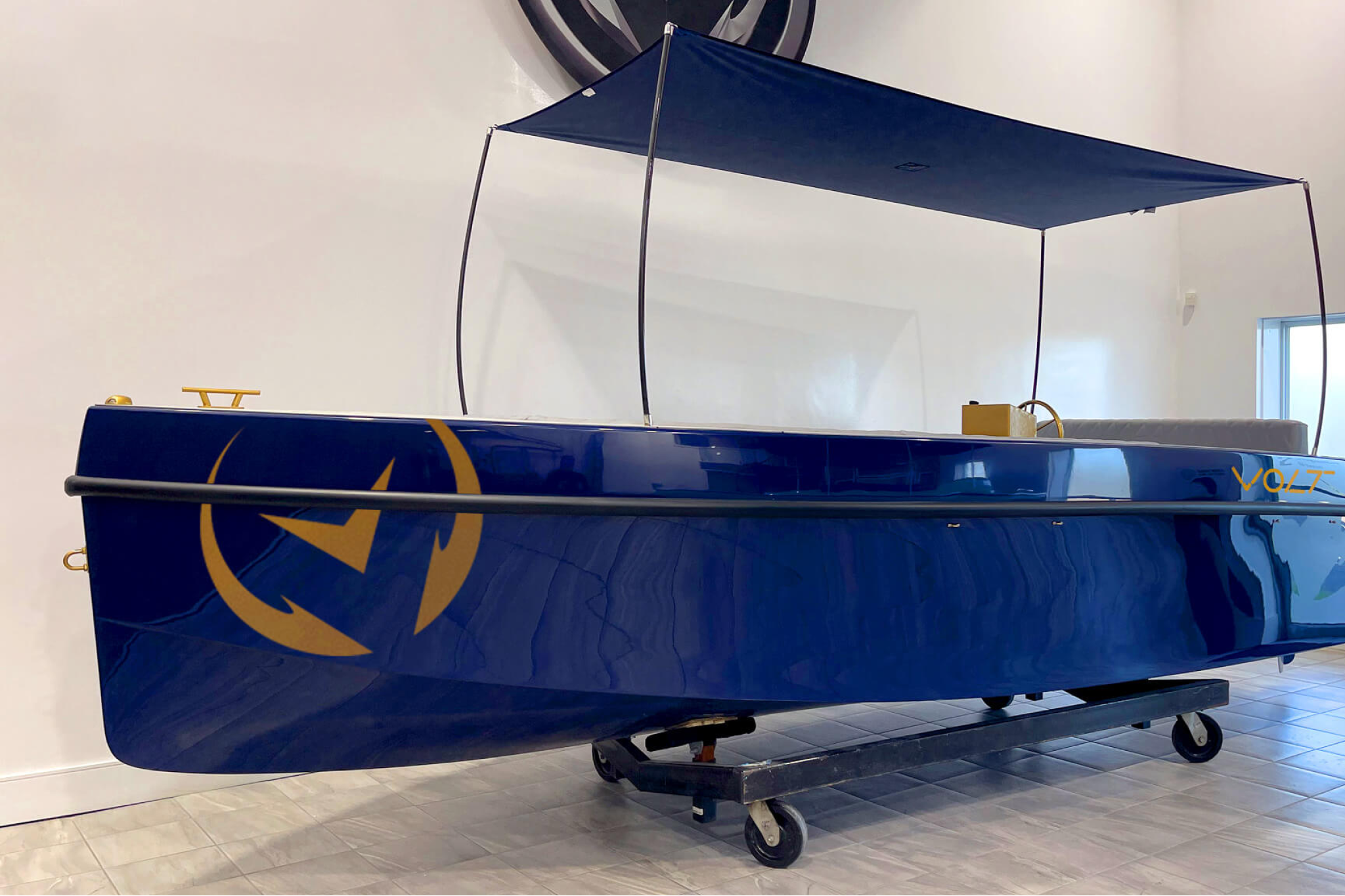 The 2025 Volt 180 displayed indoors, showing its minimalist electric boat design, canopy structure, and clean fiberglass hull as part of its key features and specifications.