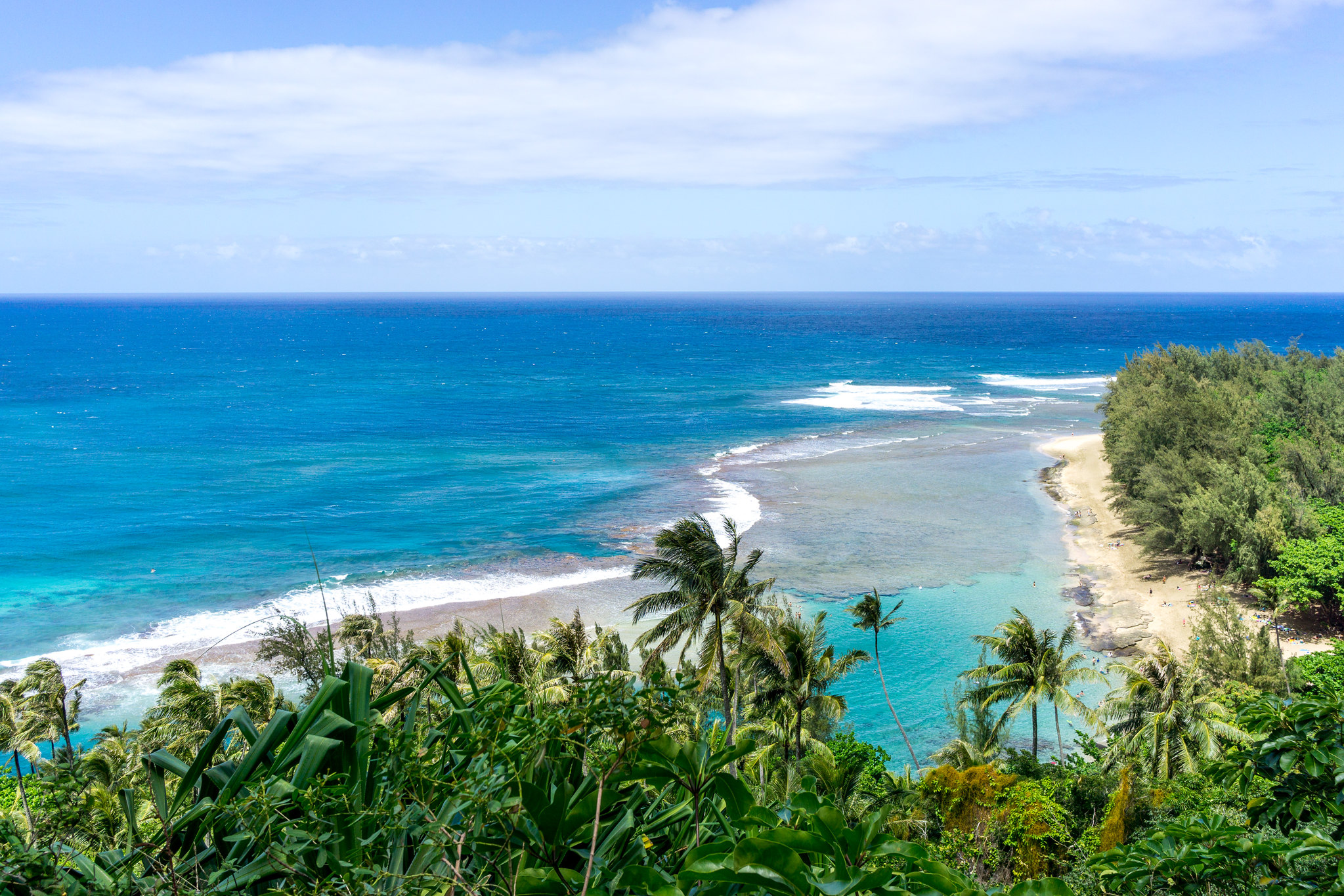 A panoramic look at Ke‘e Beach on Kauai’s north shore, with its expansive reef and deep blue waters—one of the best beaches in Kauai for summer swimming and stunning sunsets.