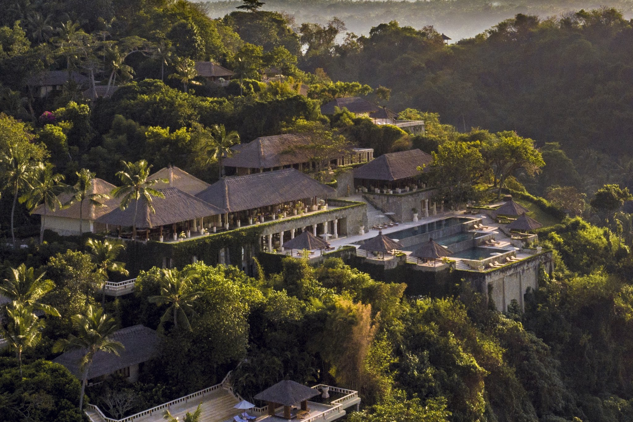 Aerial view of Amankila Bali nestled on a lush hillside overlooking the Lombok Strait