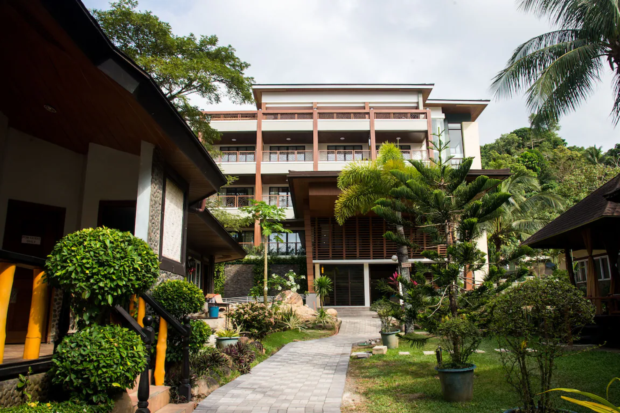 Pathway leading through tropical landscaping to the multi-level El Nido Garden Resort, with a blend of traditional and modern structures — a centrally located favorite among the best beach resorts in El Nido Palawan.
