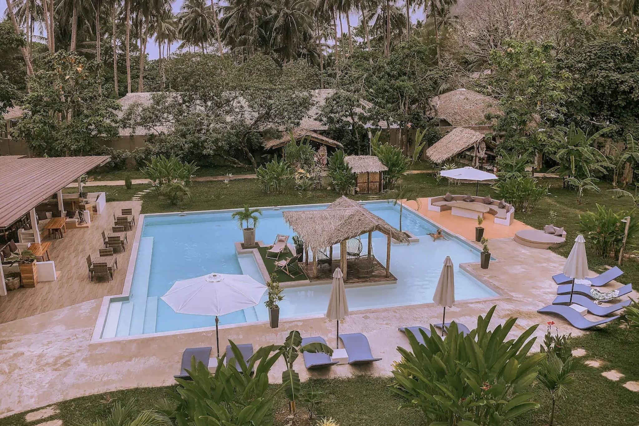Serene poolside scene at El Nido Moringa Resort in Palawan, featuring a thatched-roof cabana, loungers, and a lush garden setting — among the best beach resorts in El Nido Palawan for laid-back comfort.