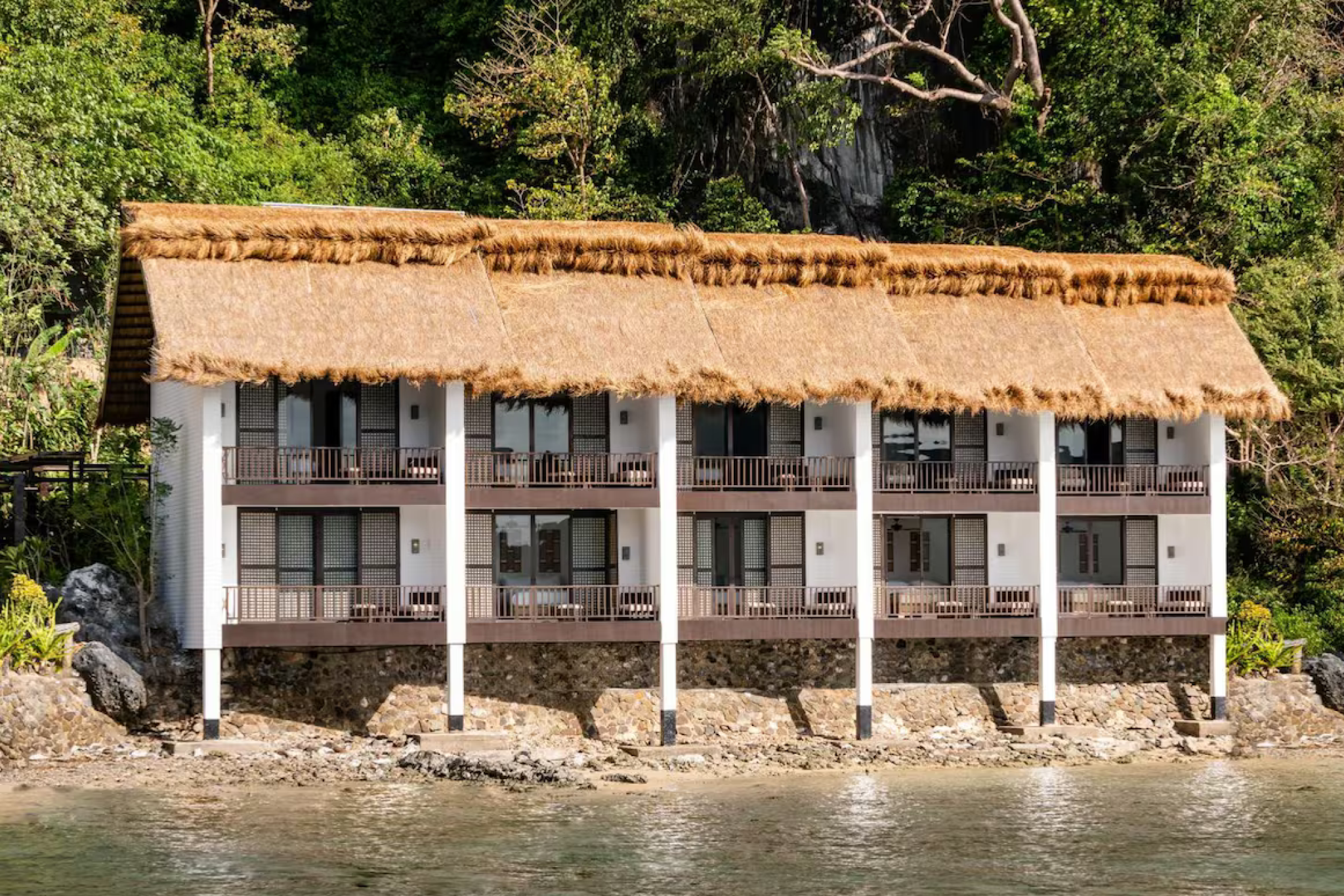 Overwater villas of Miniloc Island Resort in El Nido Palawan facing the shoreline, with a thatched roof and tropical architecture — a sustainable favorite among the best beach resorts in El Nido Palawan.