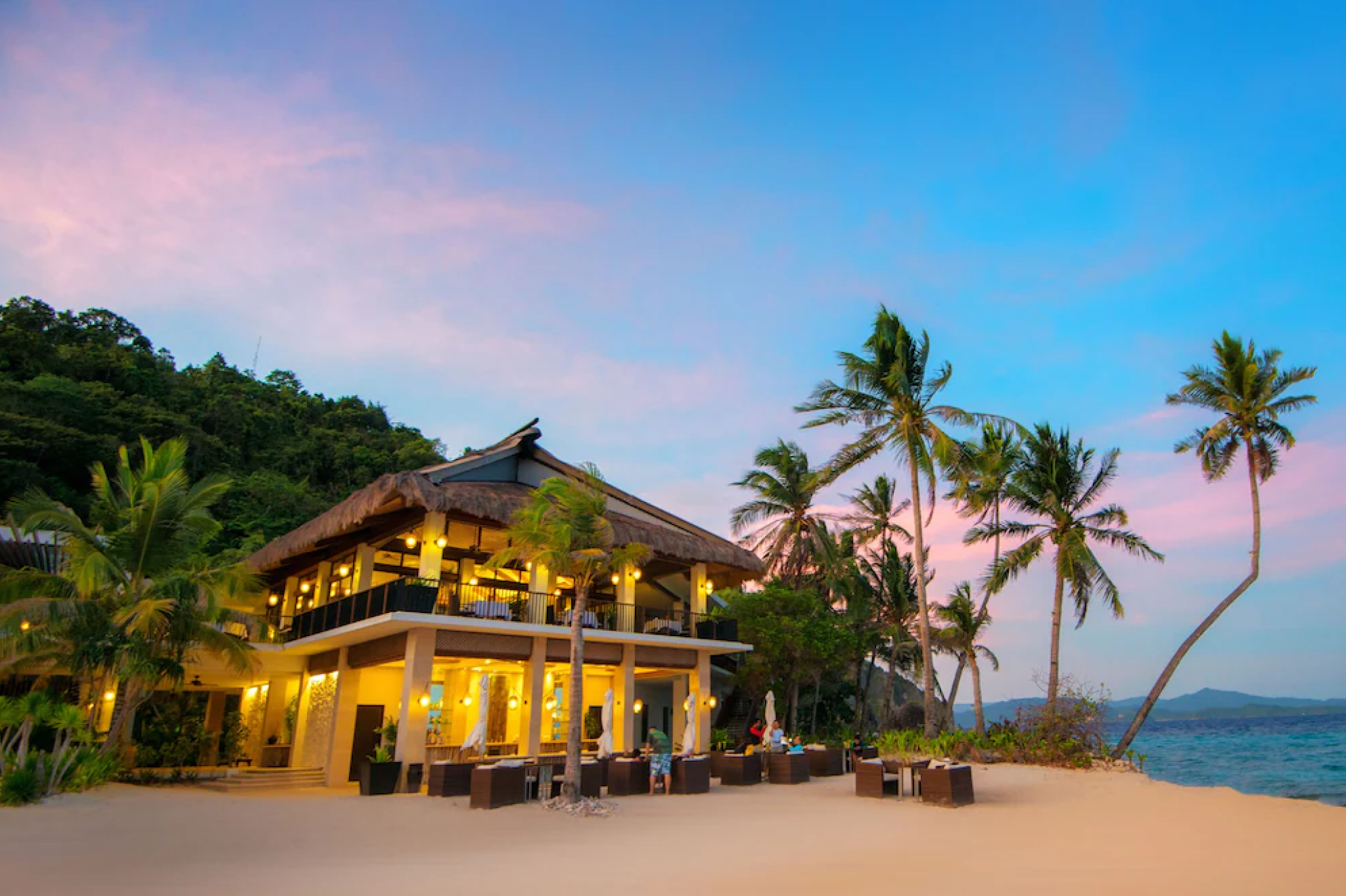 Pangulasian Island Resort at sunset in El Nido Palawan, with beachfront dining under swaying palms and luxury villas facing the sea — one of the best beach resorts in El Nido Palawan for five-star island luxury.