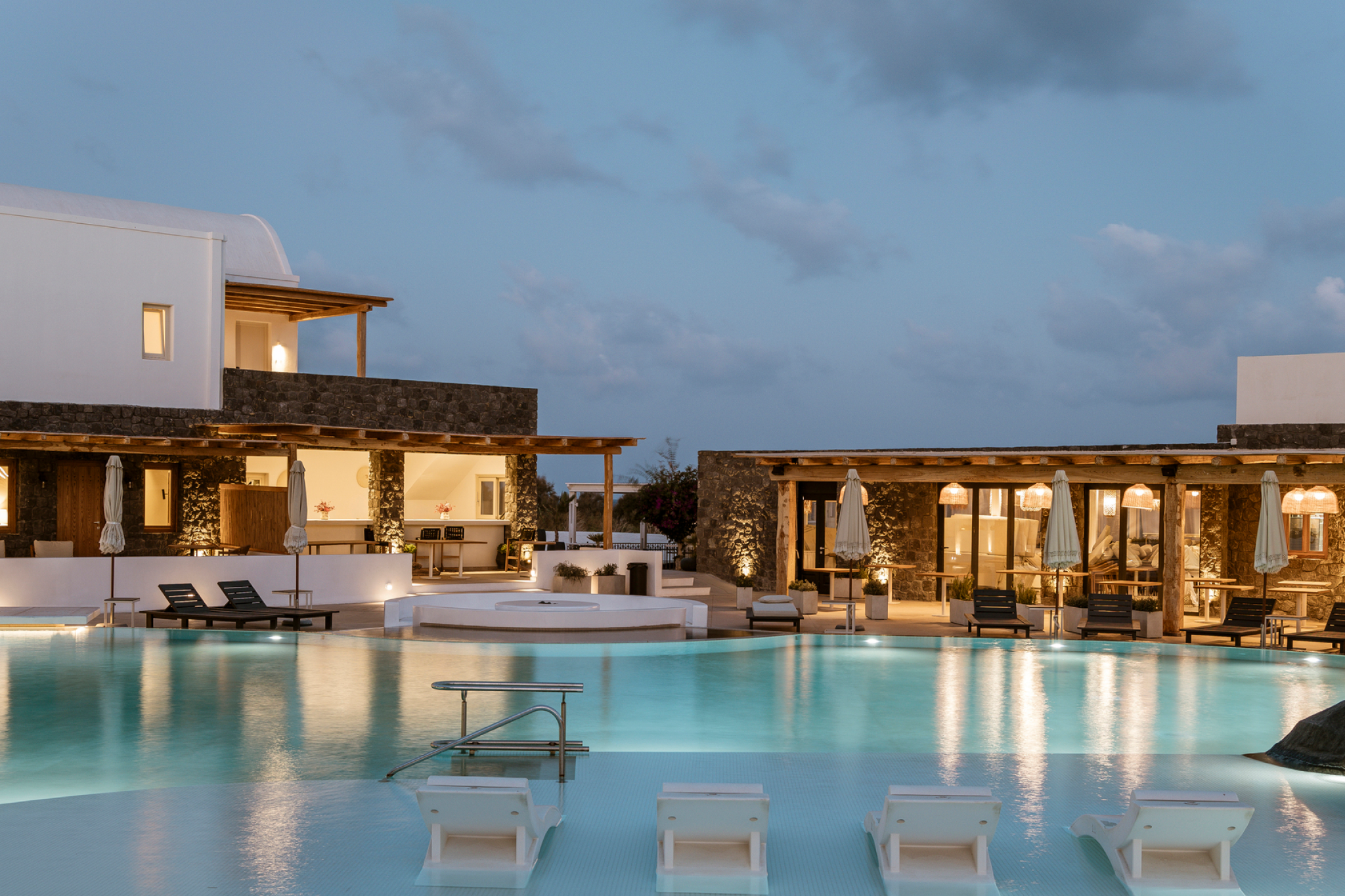 Modern façade of Amaria Beach Resort in Kamari, a stylish property ranked among the Best Beach Resorts in Santorini, showcasing white architecture and black-sand beach backdrop.