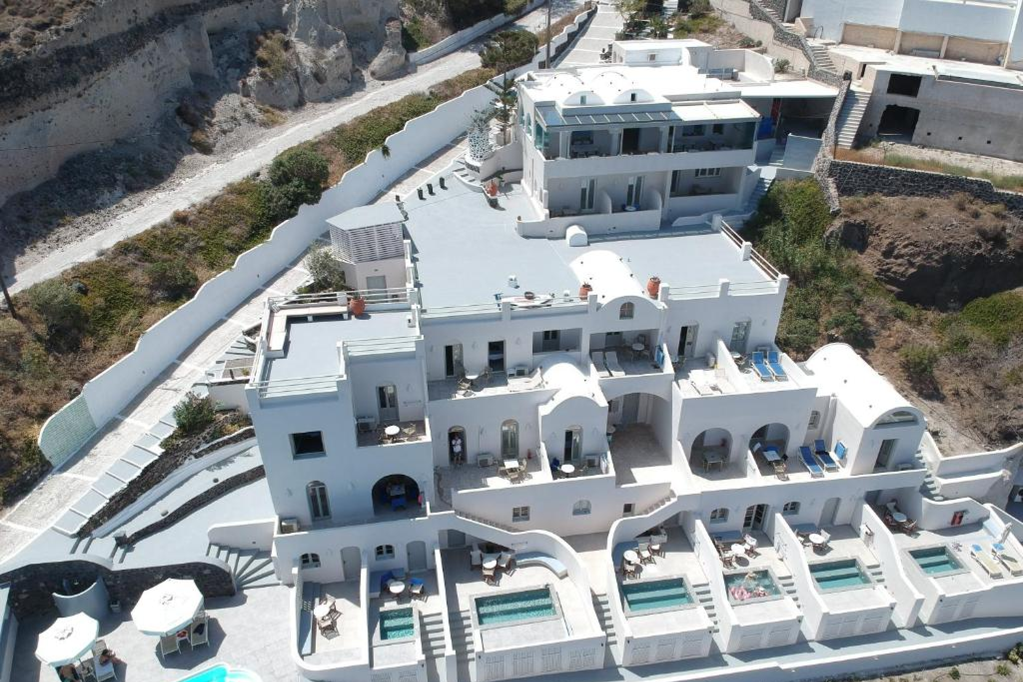 Panoramic caldera view from Kokkinos Villas in Akrotiri, featured among the Best Beach Resorts in Santorini, overlooking cliffs and the tranquil Caldera Beach below.