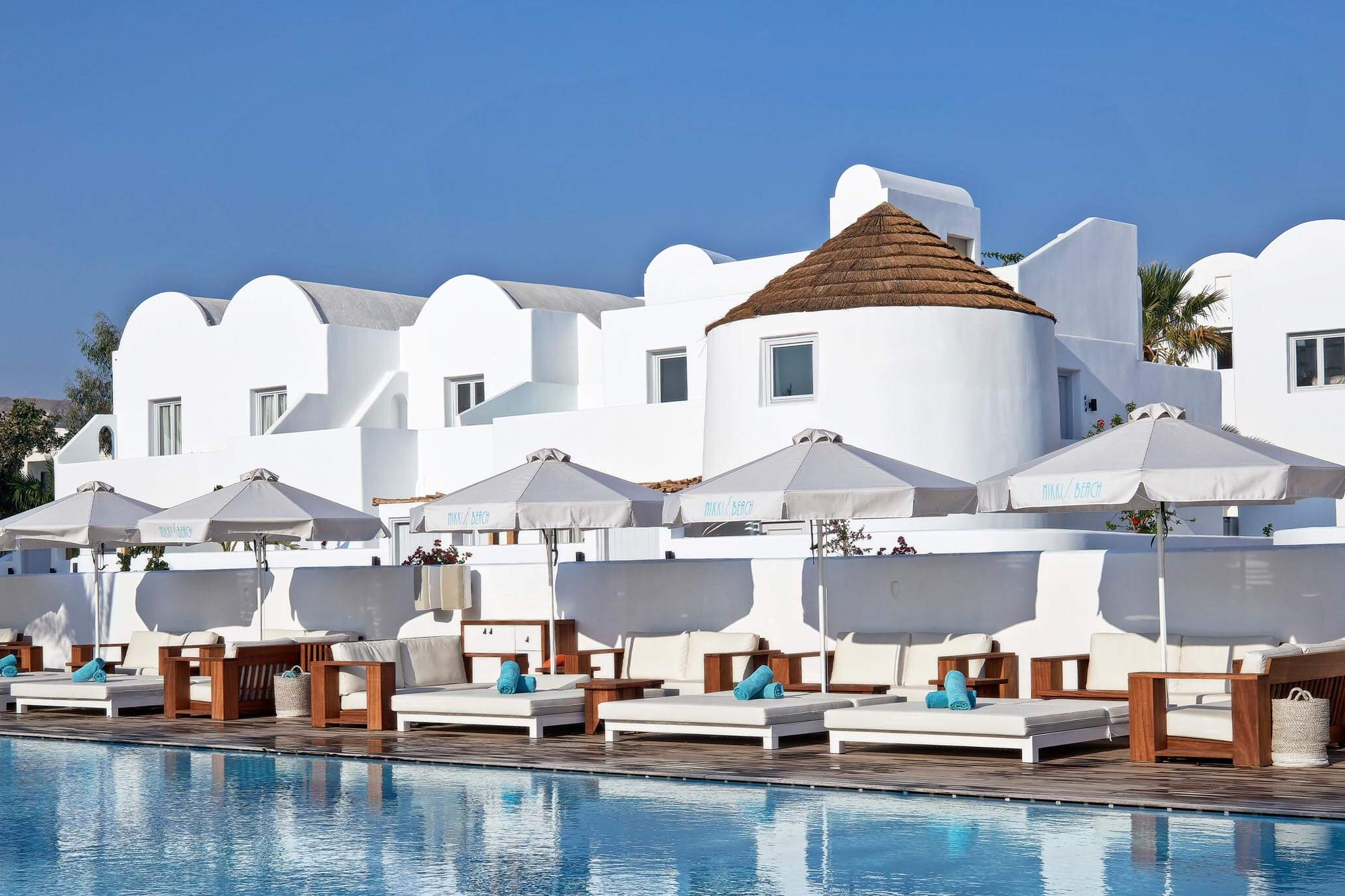 Luxury beachfront pool area at Nikki Beach Resort & Spa Santorini, the top-ranked among the Best Beach Resorts in Santorini, combining sleek design with upscale beach club vibes.