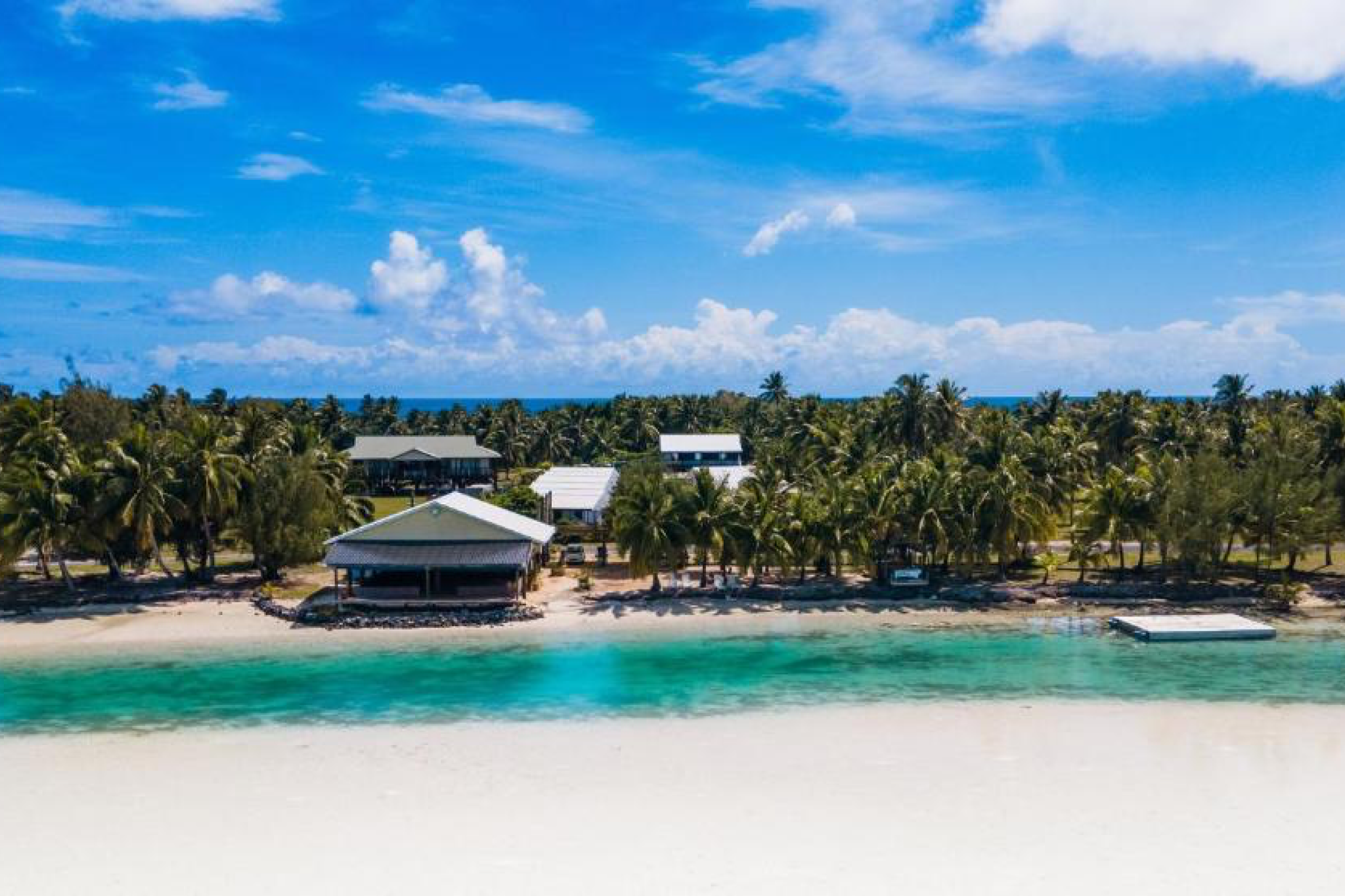 Beachfront bungalows and restaurant along Ootu Beach at Aitutaki Village, overlooking calm turquoise waters and coconut palms — a top-rated pick among the best Aitutaki resorts.