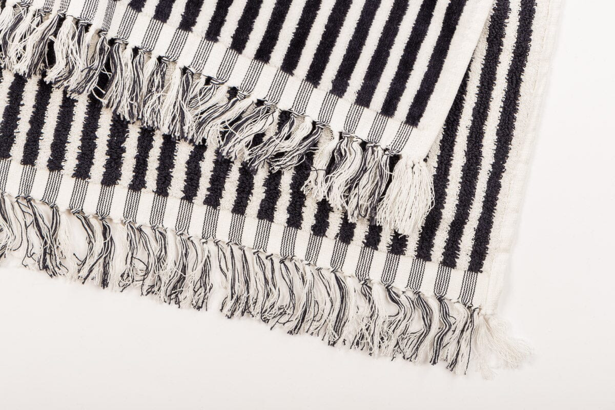 Business & Pleasure Co. beach blanket with classic black and white stripes and fringe detailing - one of the best beach blankets for coastal style