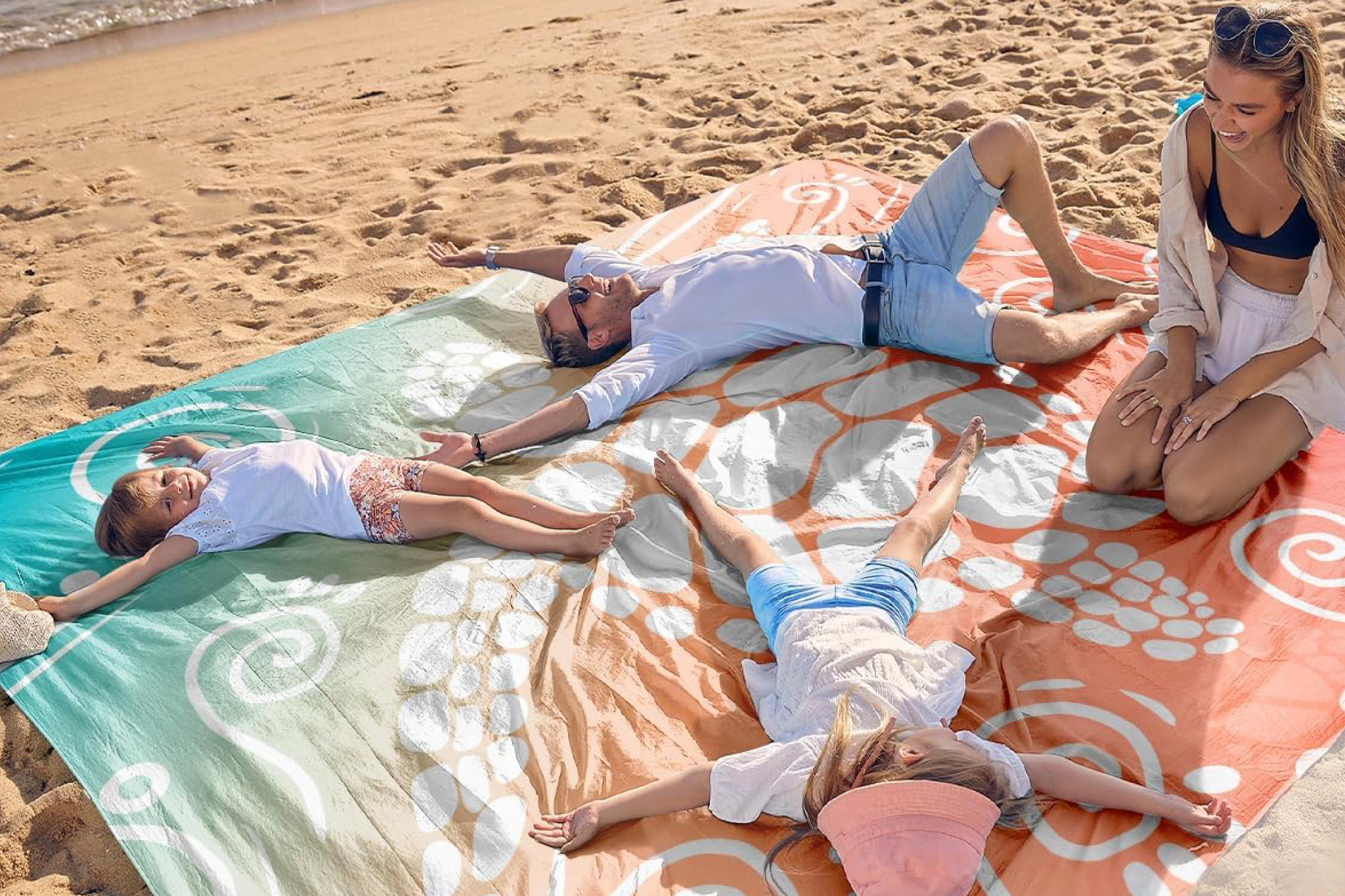 Family enjoying Sand Cloud beach blanket on sandy beach - showcasing why it's one of the best beach blankets for families