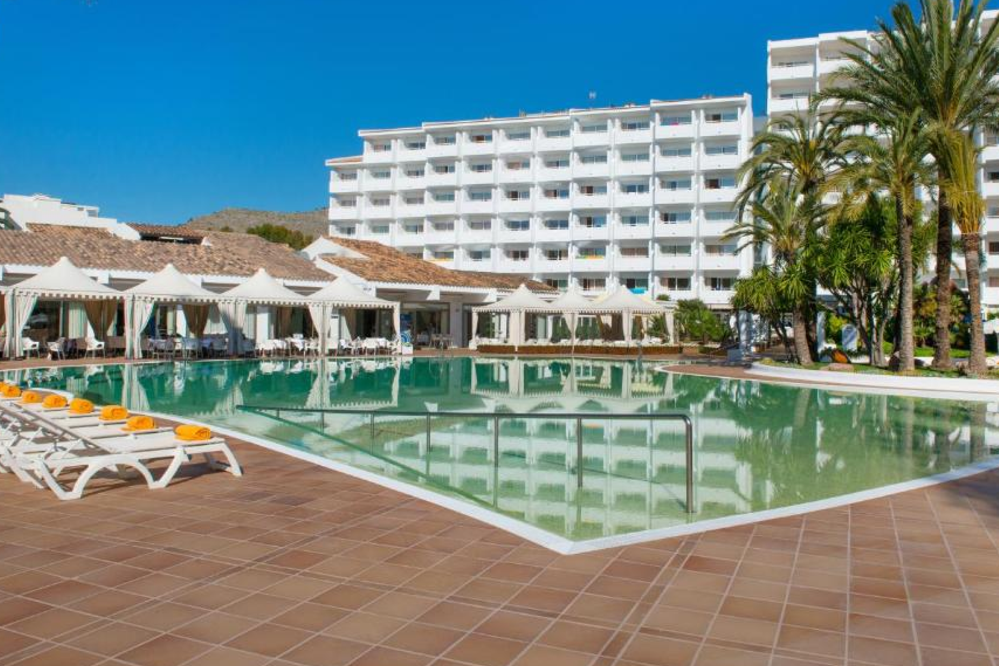Bright, family-friendly poolside area at Zafiro Palace Alcudia with white buildings, sun loungers, and clear skies — ranked among the best beach resorts in Mallorca for families and upscale all-inclusive comfort.