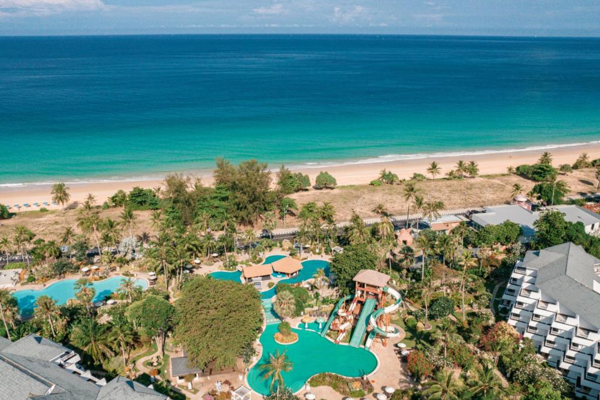 Aerial view of Thavorn Palm Beach Resort on Karon Beach with lush gardens, pools, and slides — among the best beach resorts in Phuket for families.