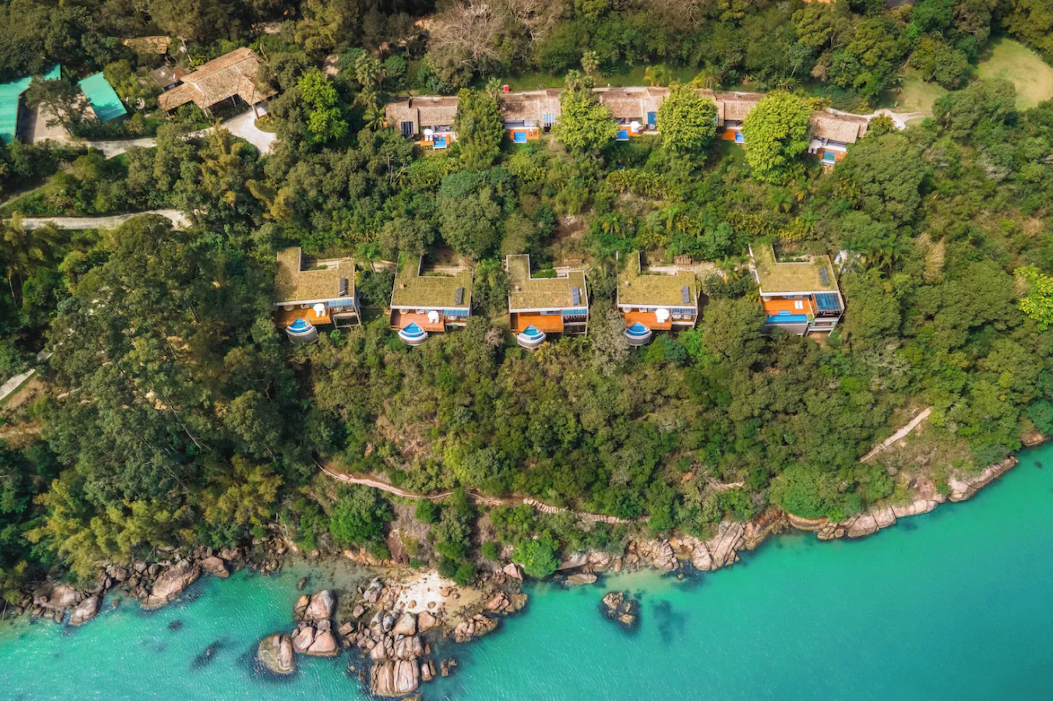 Aerial view of Ponta dos Ganchos Exclusive Resort set along a forested peninsula with private villas perched above emerald-green water and rocky coves — showcasing the secluded, cinematic setting that makes it one of the best beach resorts in South America in 2025.