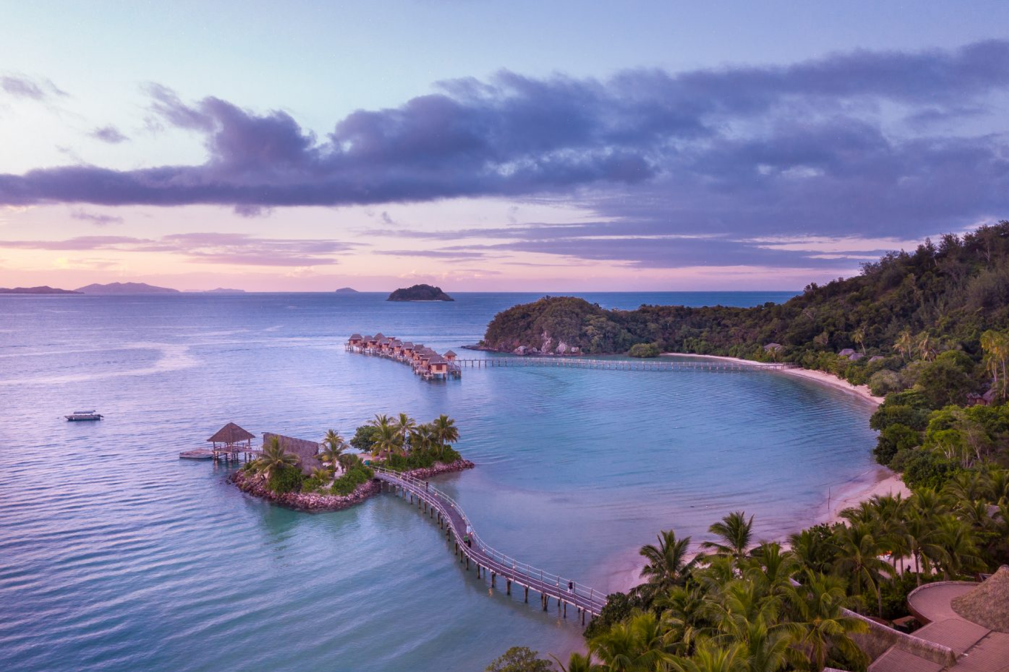 Overwater bungalows curving across a tranquil lagoon at Likuliku Lagoon Resort during sunset, reinforcing its status as one of the best beach resorts in the South Pacific in 2025.