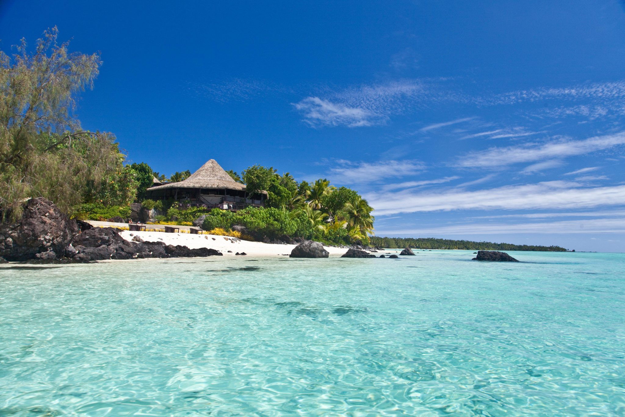 Thatched-roof beachfront pavilion at Pacific Resort Aitutaki surrounded by crystal-clear lagoon waters and white sand, representing why it ranks among the best beach resorts in the South Pacific in 2025.