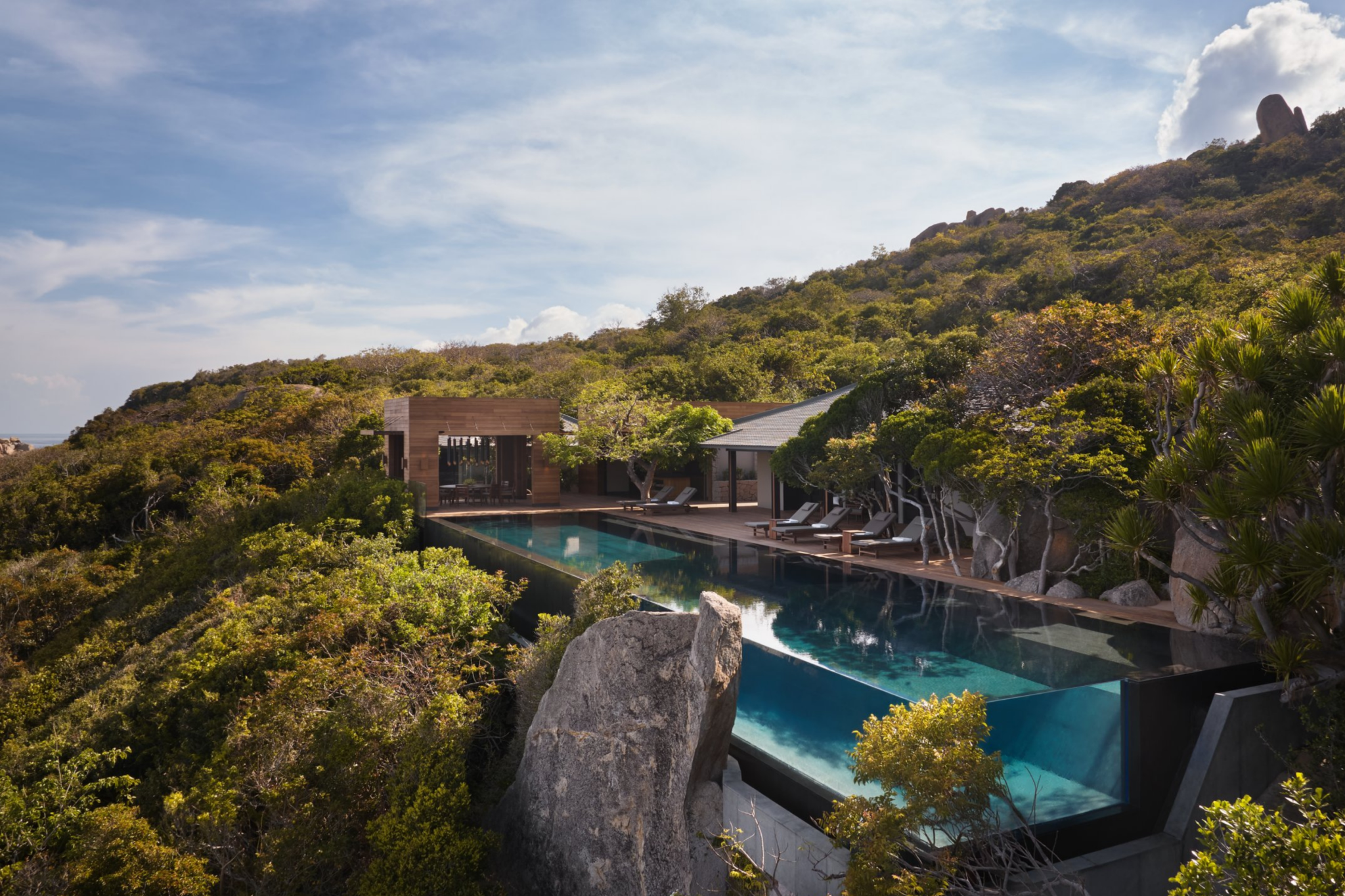 A secluded cliffside pool villa at Amanoi, ranked among the best beach resorts in Southeast Asia in 2025, with a sleek black-tiled infinity pool, modern pavilions, and rugged coastal vegetation overlooking Vinh Hy Bay.