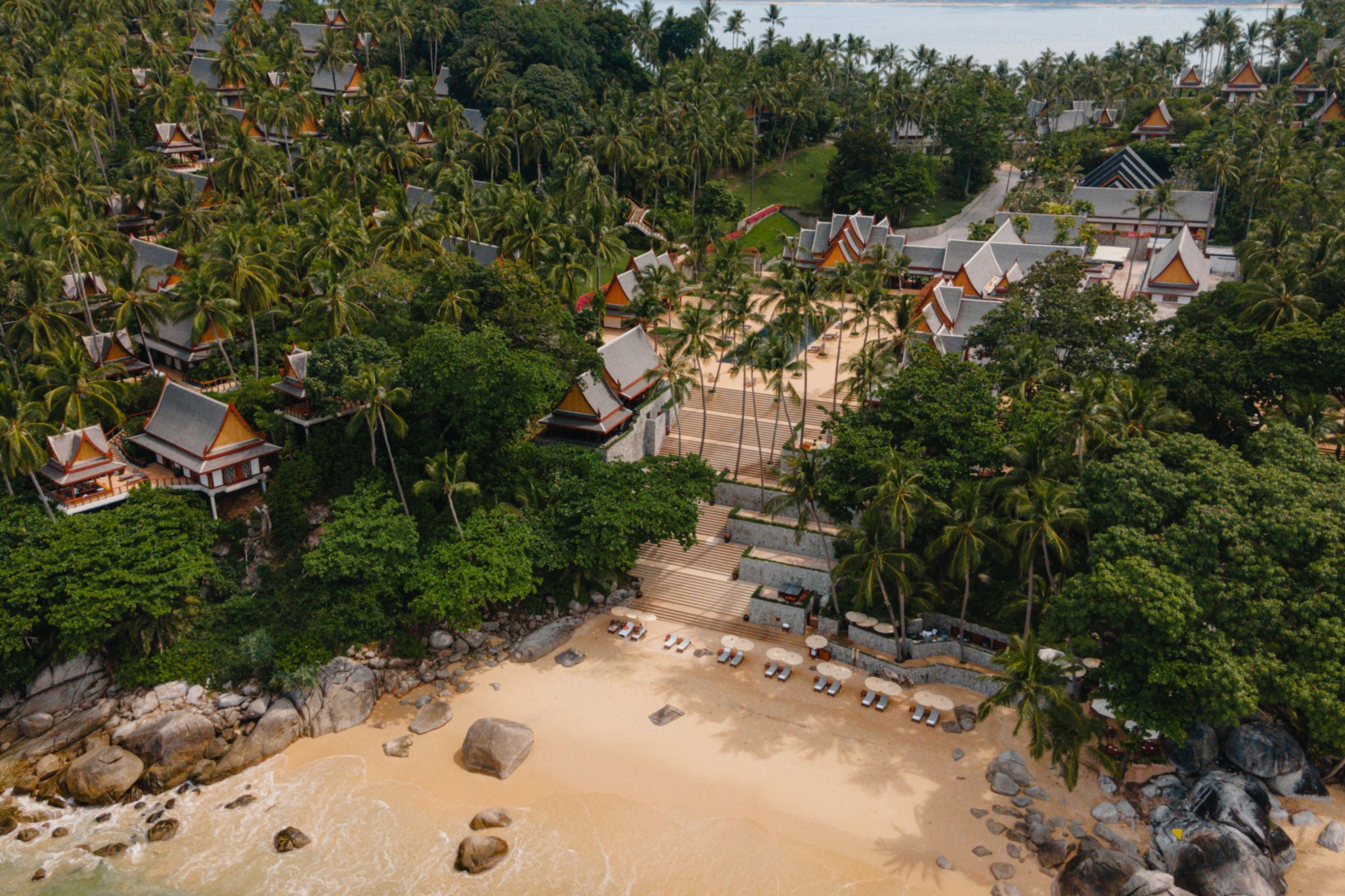 Aerial view of Amanpuri, one of the best beach resorts in Southeast Asia in 2025, showing Thai-inspired pavilions set within dense coconut groves descending toward a secluded private sandy beach.