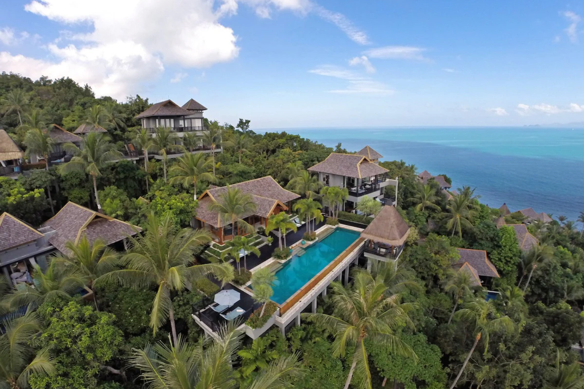 A hillside aerial view of Four Seasons Resort Koh Samui, one of the best beach resorts in Southeast Asia in 2025, featuring private pool villas nestled among lush palm trees overlooking the turquoise Gulf of Thailand.