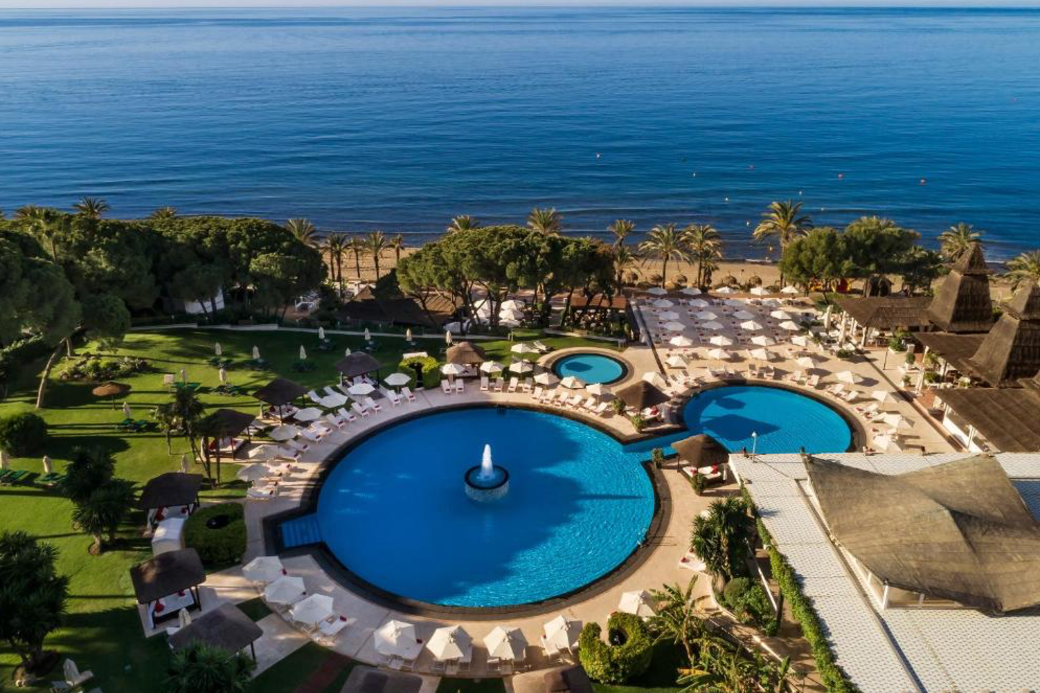 Hotel Don Pepe Gran Meliá viewed from above, displaying its circular pools, manicured lawns, and beachside loungers leading to the Mediterranean Sea — a refined icon within the best beach resorts in Spain.