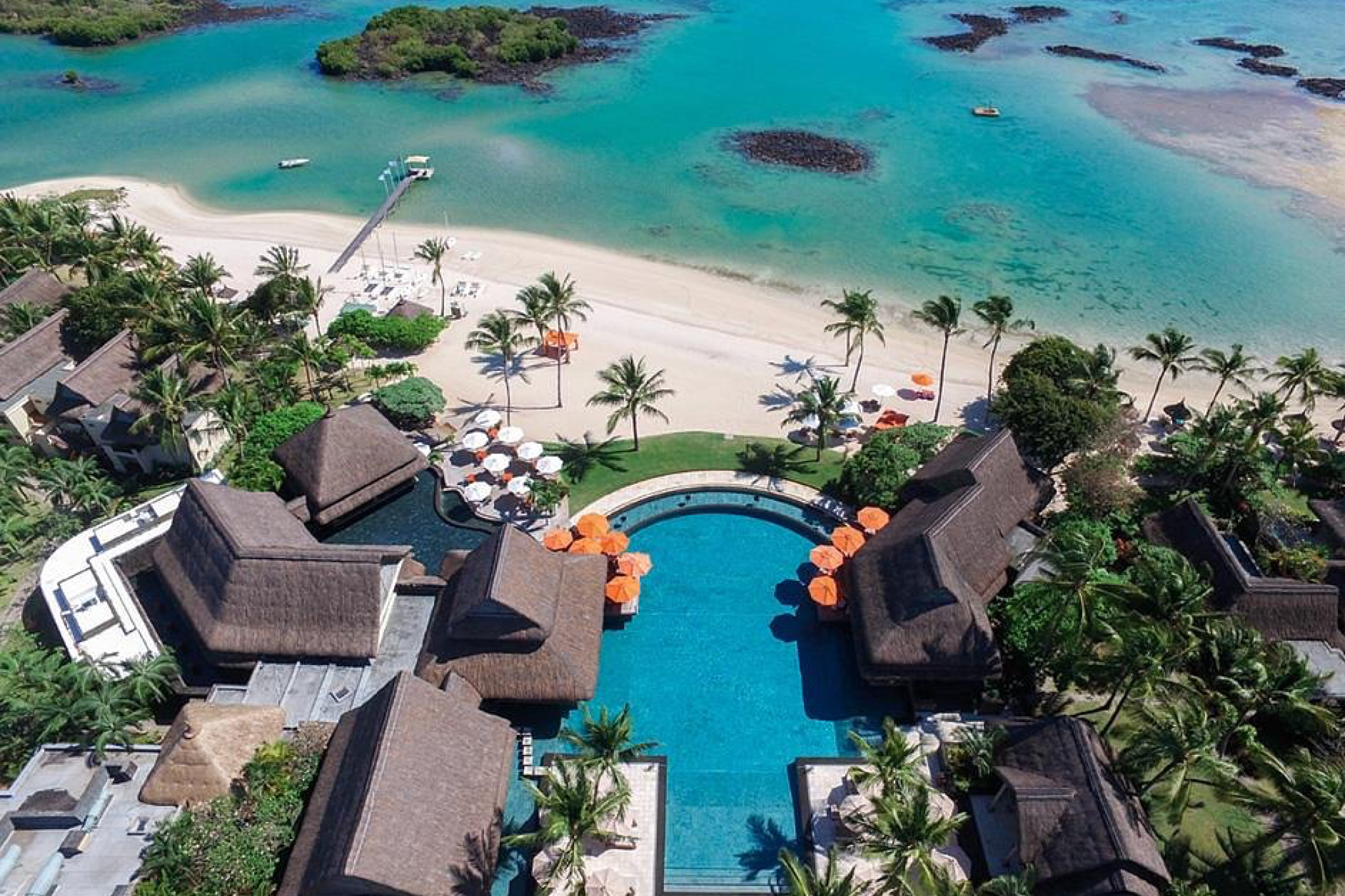 Aerial photograph of Constance Prince Maurice featuring its sweeping beachfront, turquoise lagoon, and central infinity pool framed by palm trees, showcasing the serene luxury that places it among the best beach resorts in the Indian Ocean in 2025.