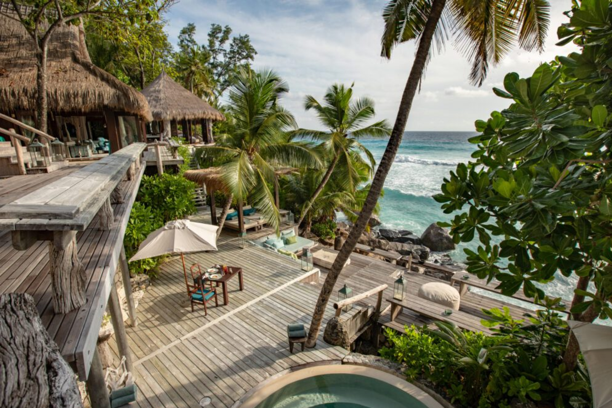 Ground-level view of North Island’s rustic, handcrafted villas surrounded by lush foliage and overlooking the Indian Ocean, emphasizing its ultra-private, nature-integrated luxury as one of the best beach resorts in the Indian Ocean in 2025.