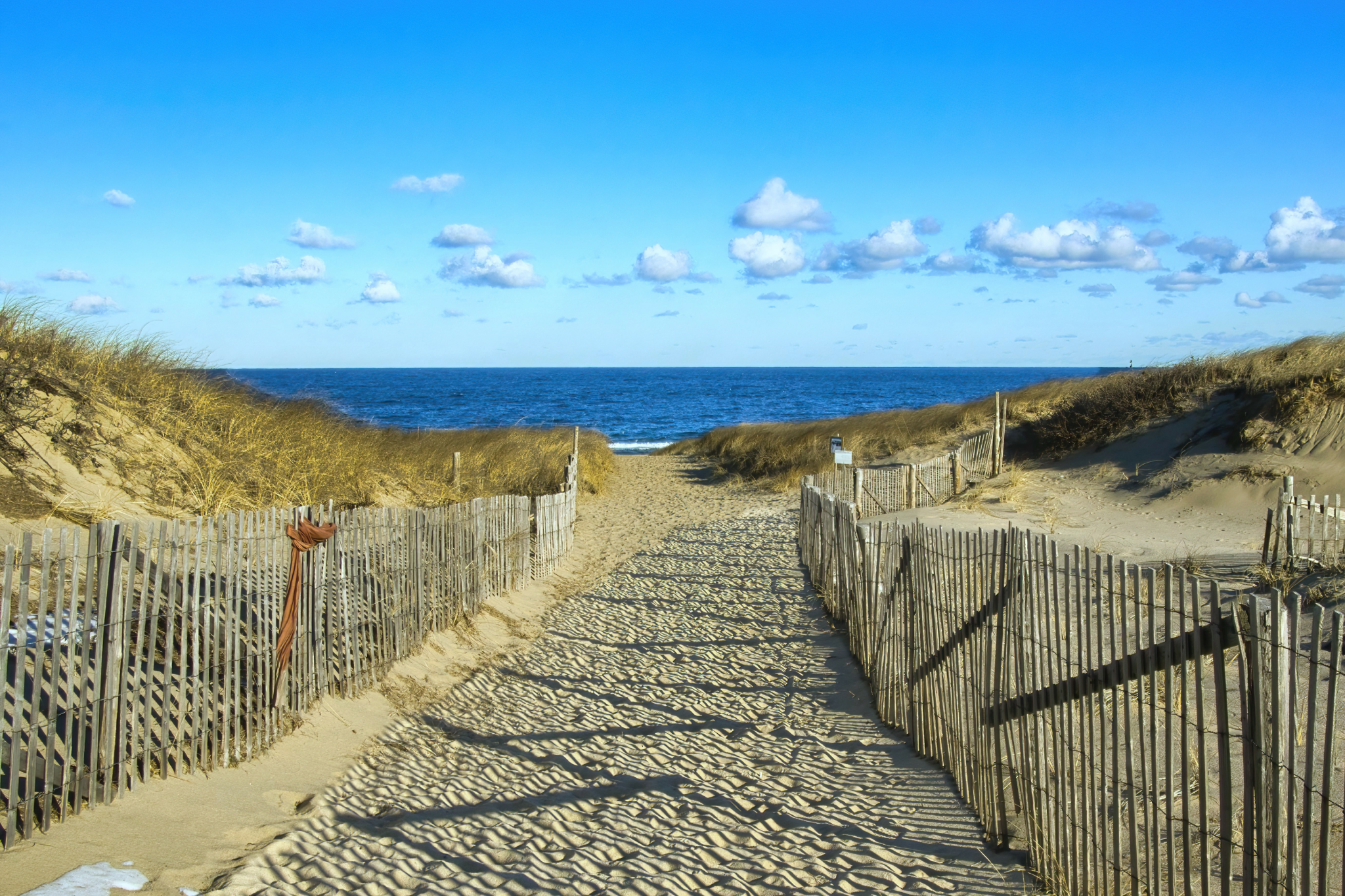 Sandy boardwalk pathway through pristine dunes leading to Race Point Beach Cape Cod, one of the best beaches on the US East Coast for natural beauty"