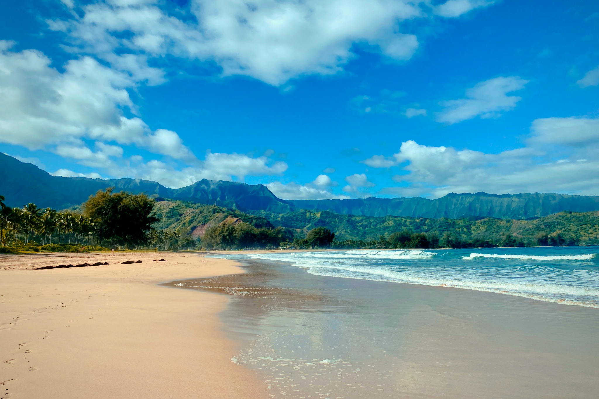 Hanalei Bay’s wide stretch of golden sand with lush mountains rising behind—this north shore gem is among the best beaches in Kauai for scenic beauty and paddleboarding.