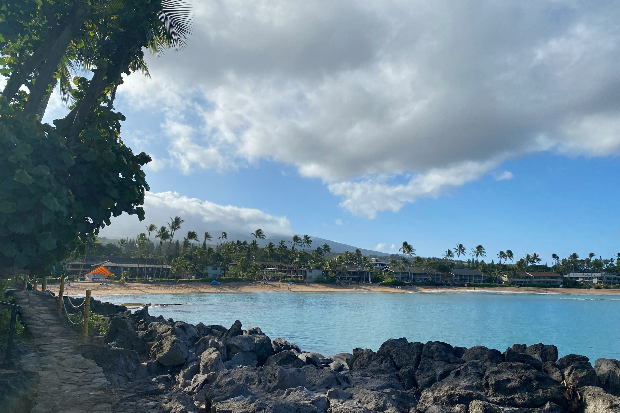 Clear blue waters and sandy shore at Napili Bay, one of the best beaches in Maui, offering a tranquil and family-friendly coastal retreat.