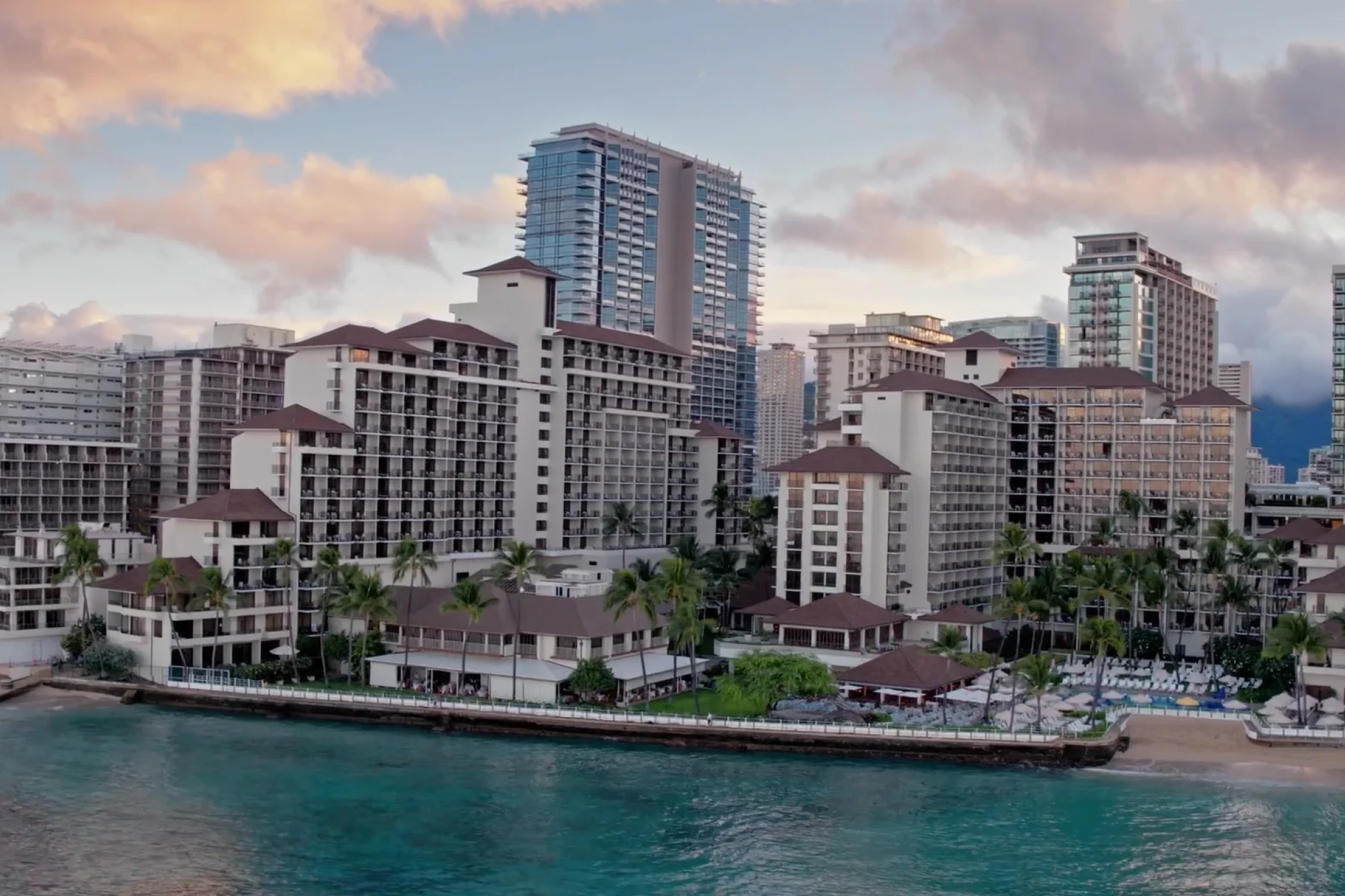 Halekulani hotel white architecture oceanfront view among best beachfront hotels in Waikiki with turquoise waters and sunset sky