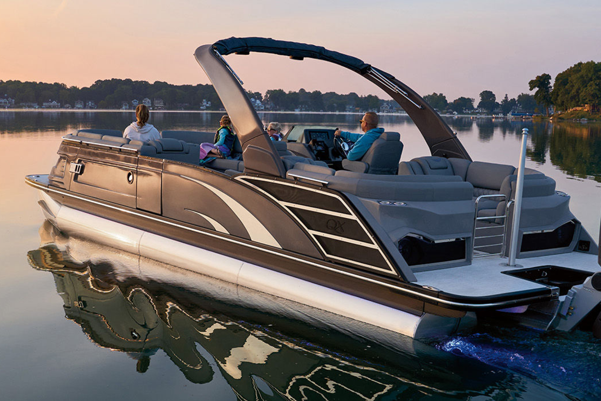 Bennington 30QX pontoon boat, one of the best boats for families, with passengers enjoying evening cruise on calm lake