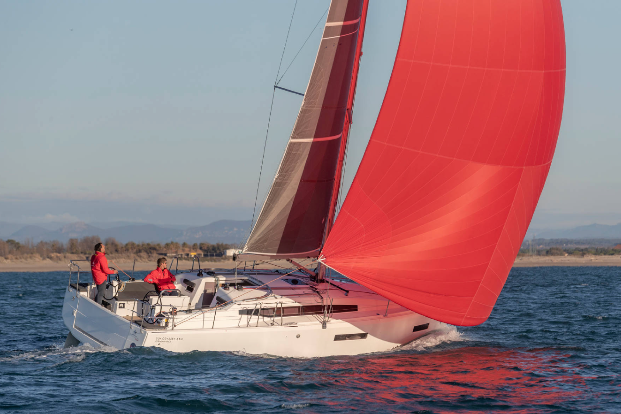 Jeanneau Sun Odyssey 380 sailboat with red spinnaker, listed among the best boats for families for sailing adventures