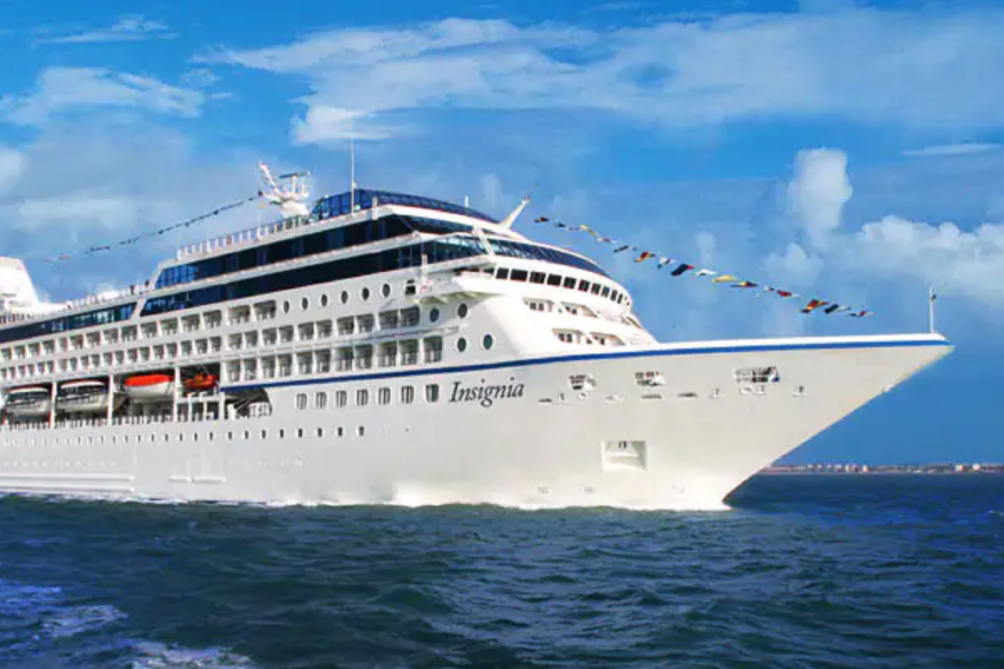 Oceania Cruises Insignia sailing with colorful flags, one of the best cruise lines for couples seeking gourmet experiences