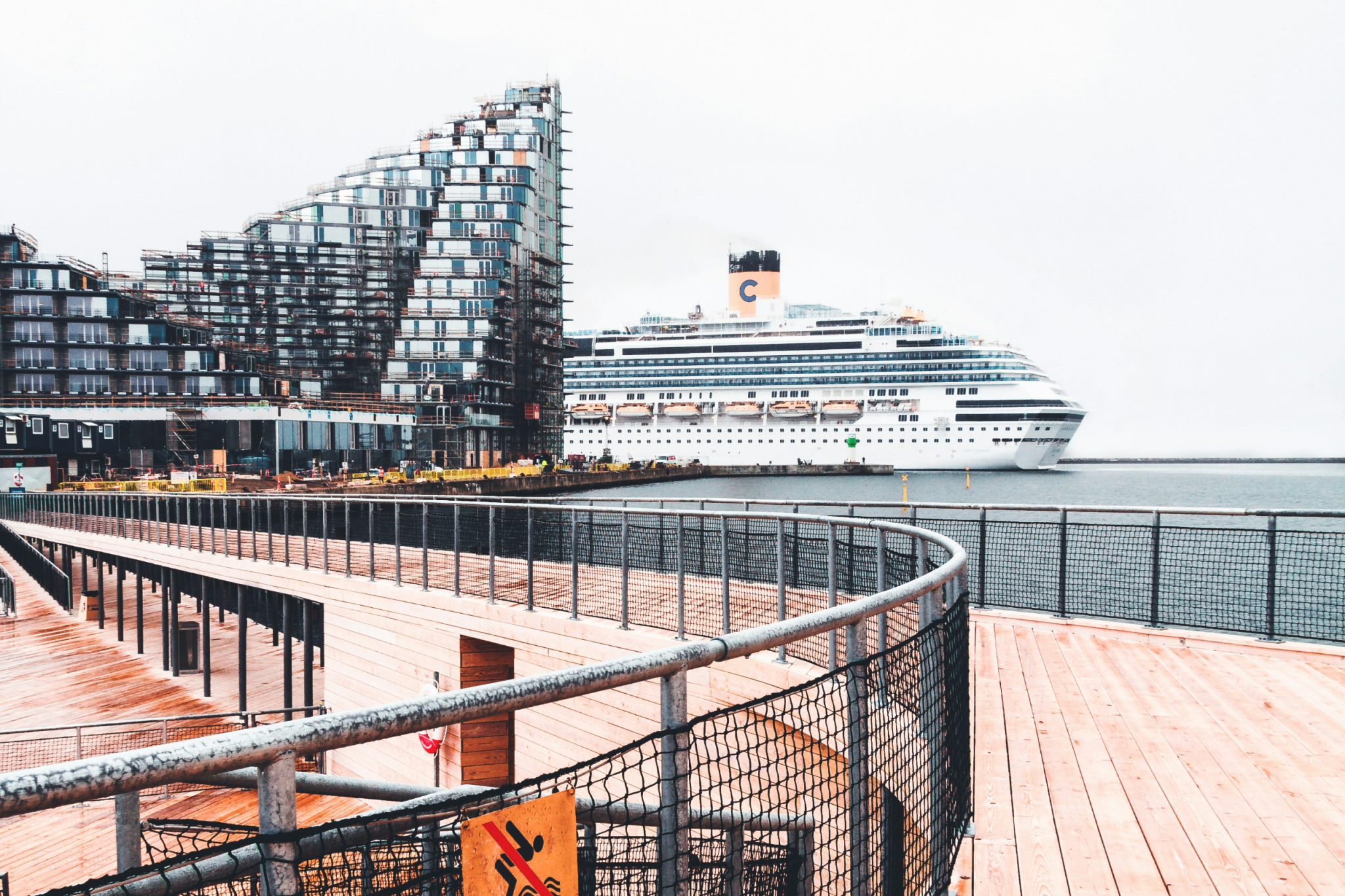 Port view of a large cruise ship docked near Copenhagen’s urban skyline, showcasing smooth embarkation and cultural access, earning it a spot as one of the best cruise ports in 2025.