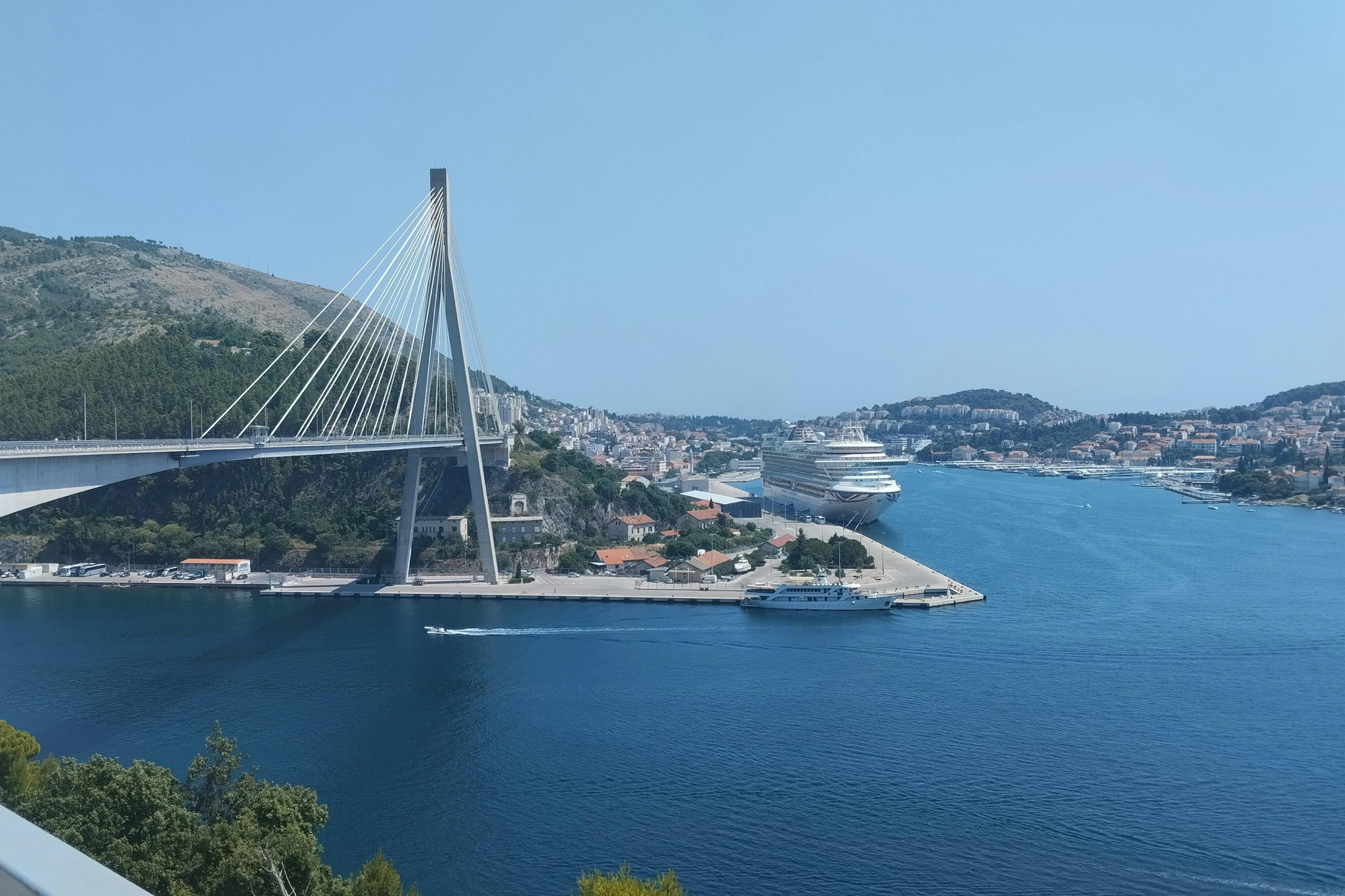 Cruise ship anchored near Dubrovnik with the city’s famous cable-stayed bridge in the background, emphasizing scenic Adriatic coastline and historic charm, a standout among the best cruise ports in 2025.