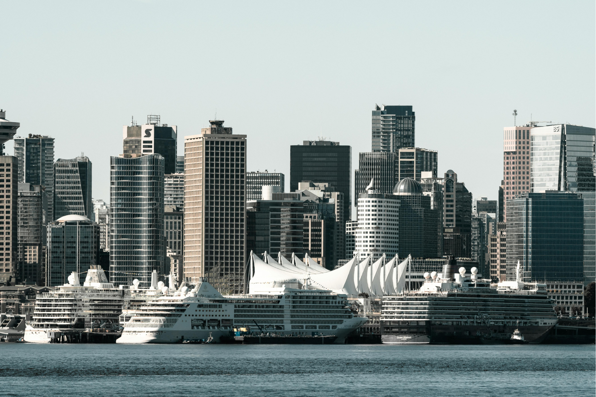 Wide-angle image of multiple cruise ships docked at Vancouver’s waterfront, with the city skyline and nearby mountains, highlighting scenic beauty and efficient port operations, ranking it among the best cruise ports in 2025.