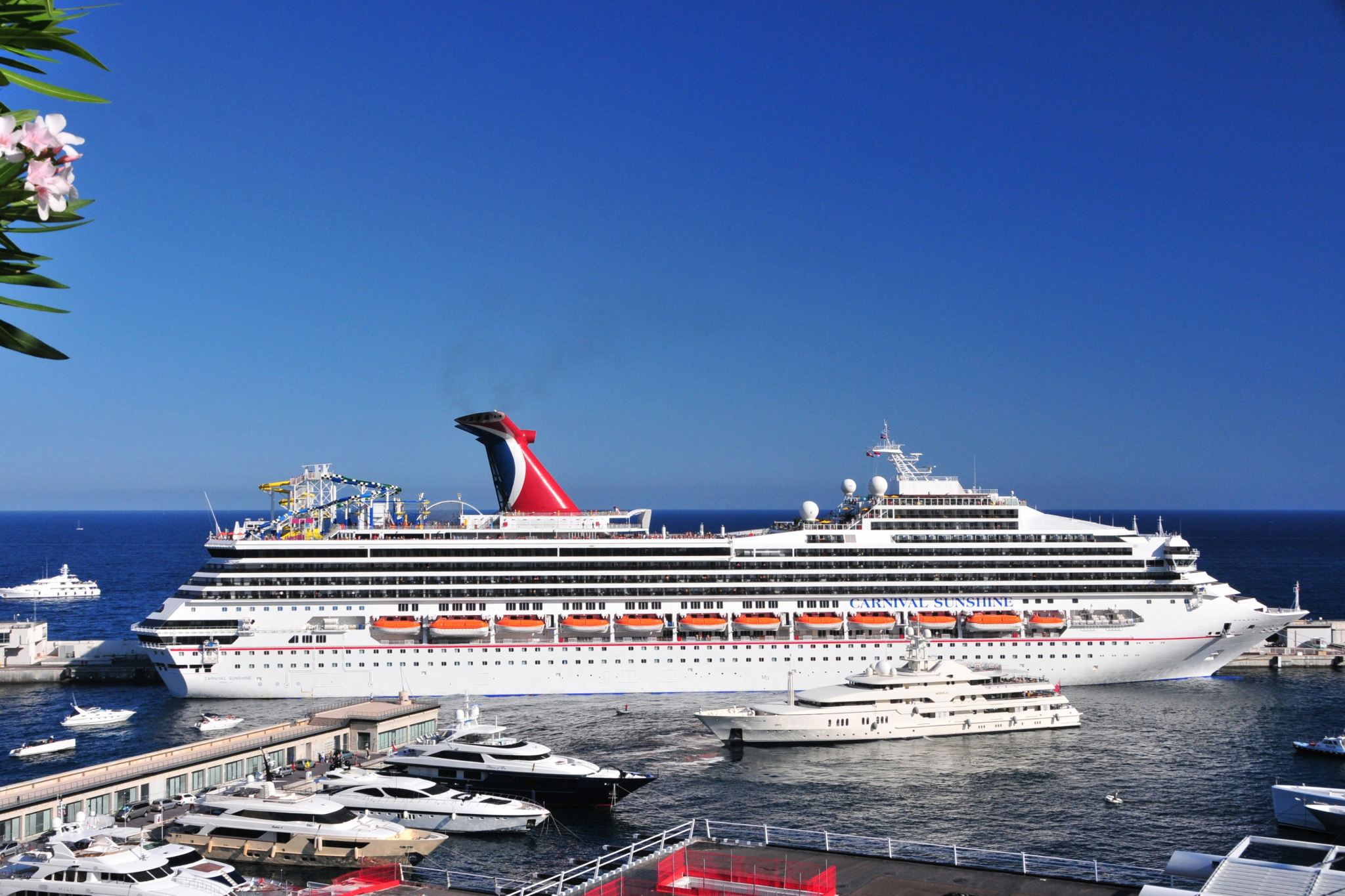 Carnival Sunshine docked near luxury yachts under clear skies — a festive and affordable option among the best cruises for Christmas.
