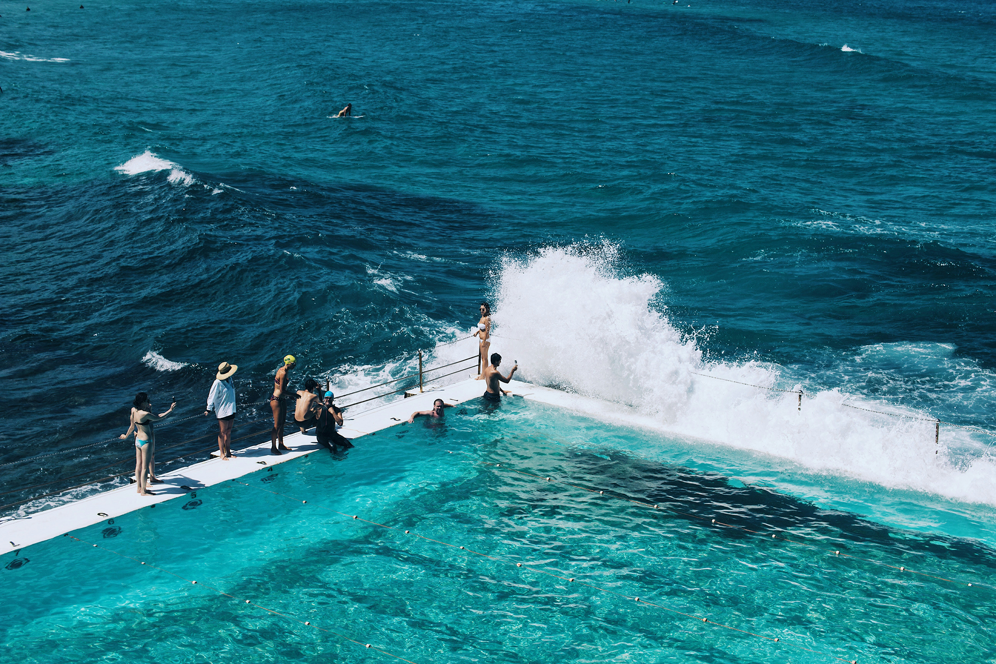Swimmers enjoying the Bondi Icebergs ocean pool as waves crash in from the Pacific, capturing the vibrant surf culture of one of the best destinations for Christmas on the beach in the Southern Hemisphere.