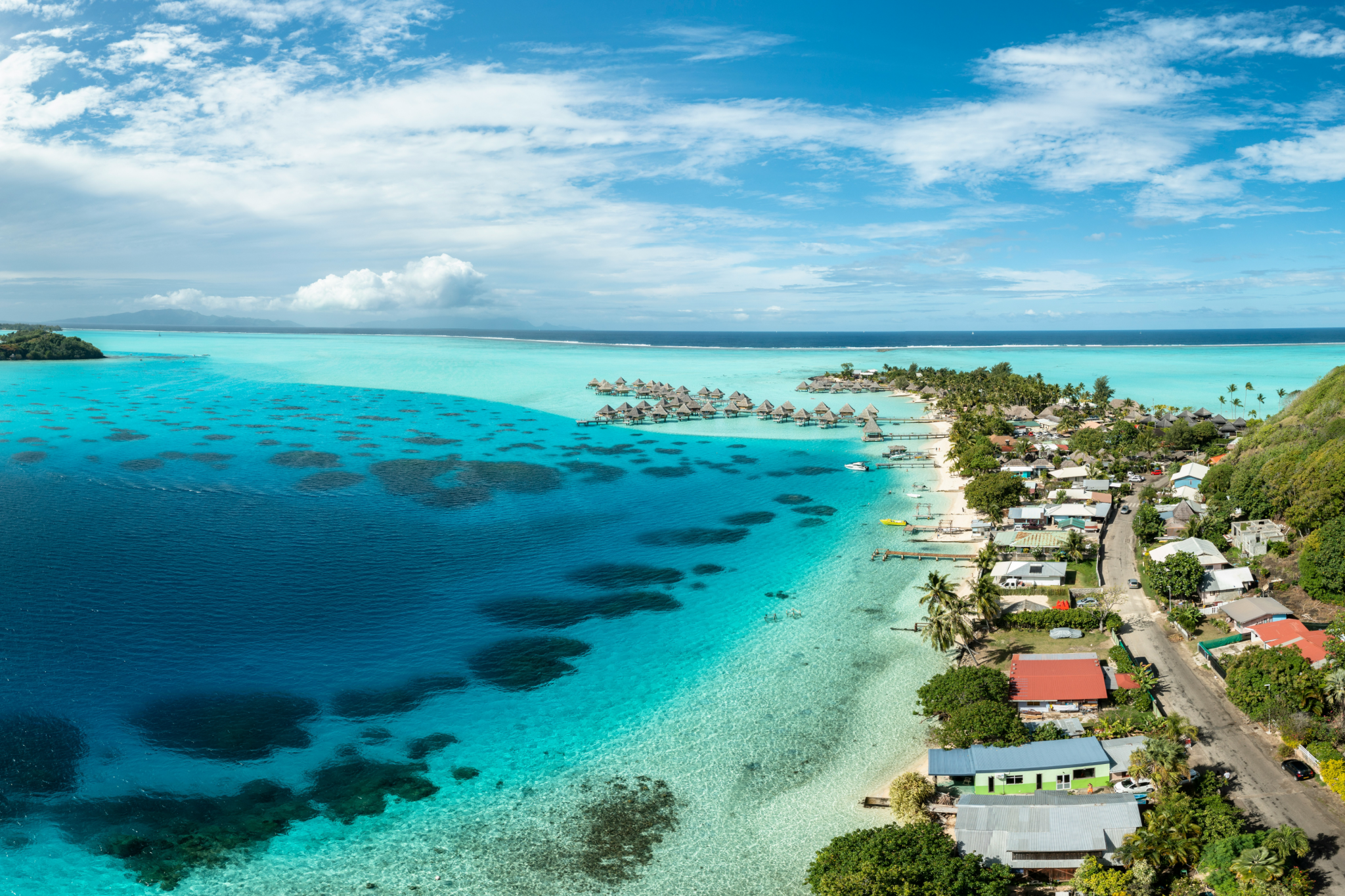 A panoramic view of Bora Bora’s lagoon with overwater villas and turquoise shallows, embodying one of the most exclusive and best destinations for Christmas on the beach.