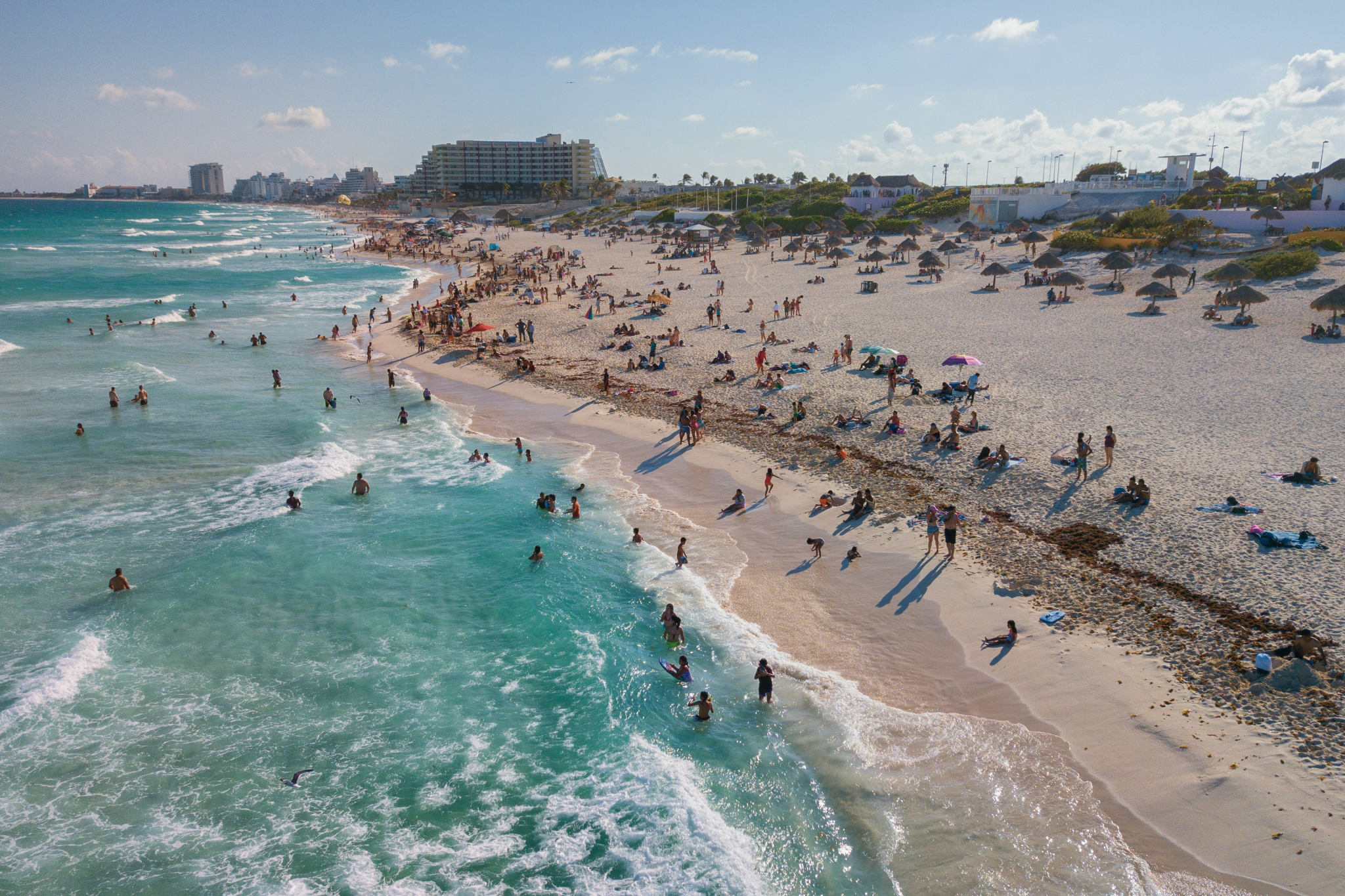 A sun-drenched beach in Cancun packed with festive travelers enjoying turquoise waves and soft sand, representing one of the best destinations for Christmas on the beach for warm weather and nightlife.