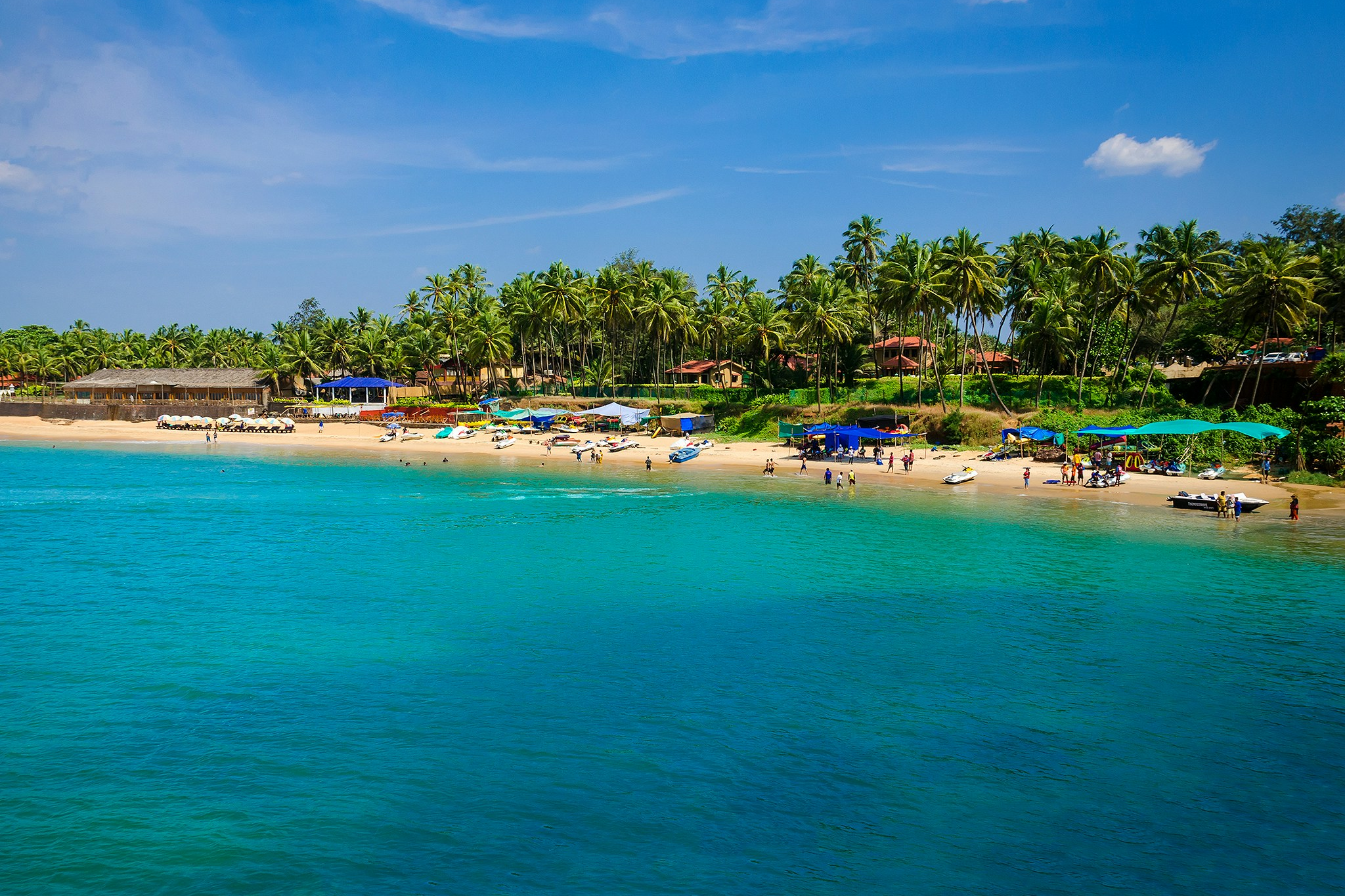 A vibrant stretch of Palolem Beach in Goa, India, showing colorful beach shacks, swaying palm trees, and holidaymakers enjoying the tropical sun — a top pick among the best destinations for Christmas on the beach.