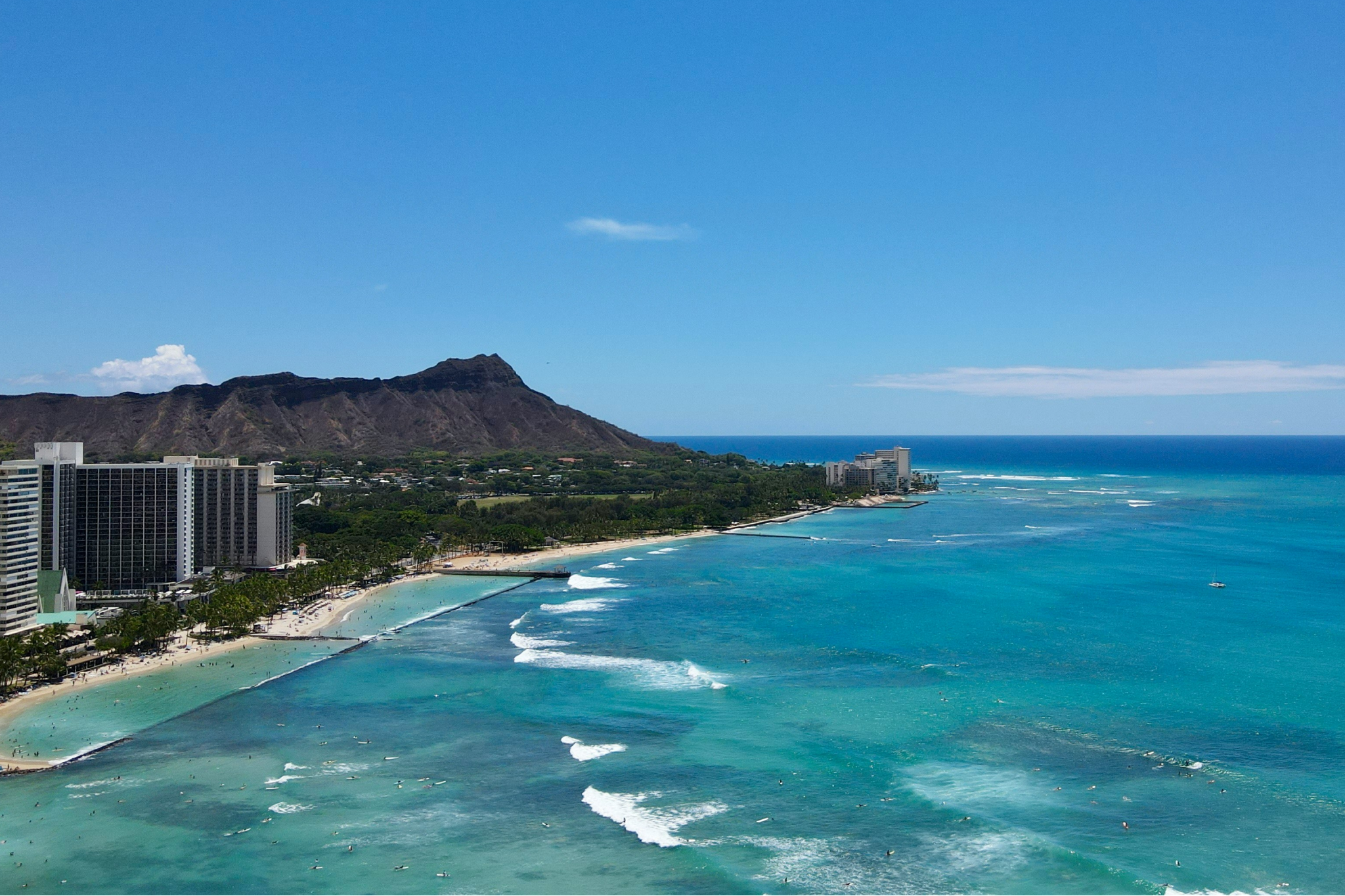 A sweeping view of Waikiki Beach with hotels lining the shore and Diamond Head in the distance, offering iconic scenery in one of the best destinations for Christmas on the beach in the U.S.