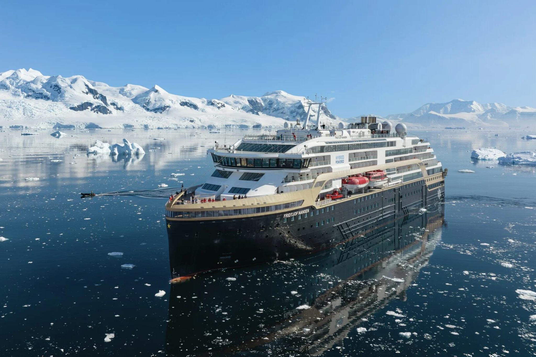 Hurtigruten’s Fridtjof Nansen hybrid-powered ship sailing past Antarctic icebergs, proof of sustainable innovation among the best expedition cruise lines.
