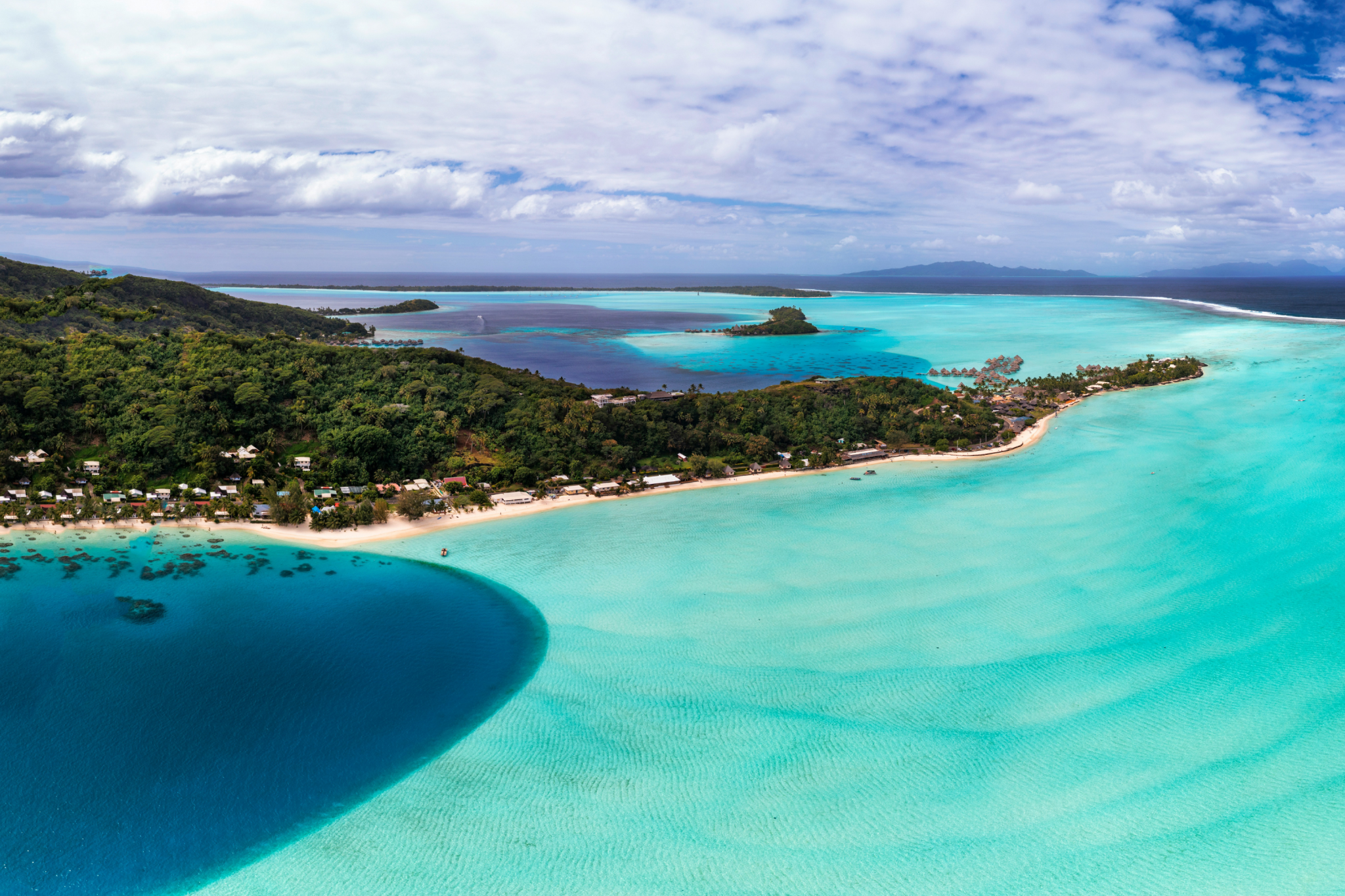 Sweeping aerial view of Bora Bora’s luminous turquoise lagoon, coral reefs, and forested motus stretching toward the horizon — capturing the dreamlike scenery that secures Bora Bora’s spot as the best island in the world in 2025.