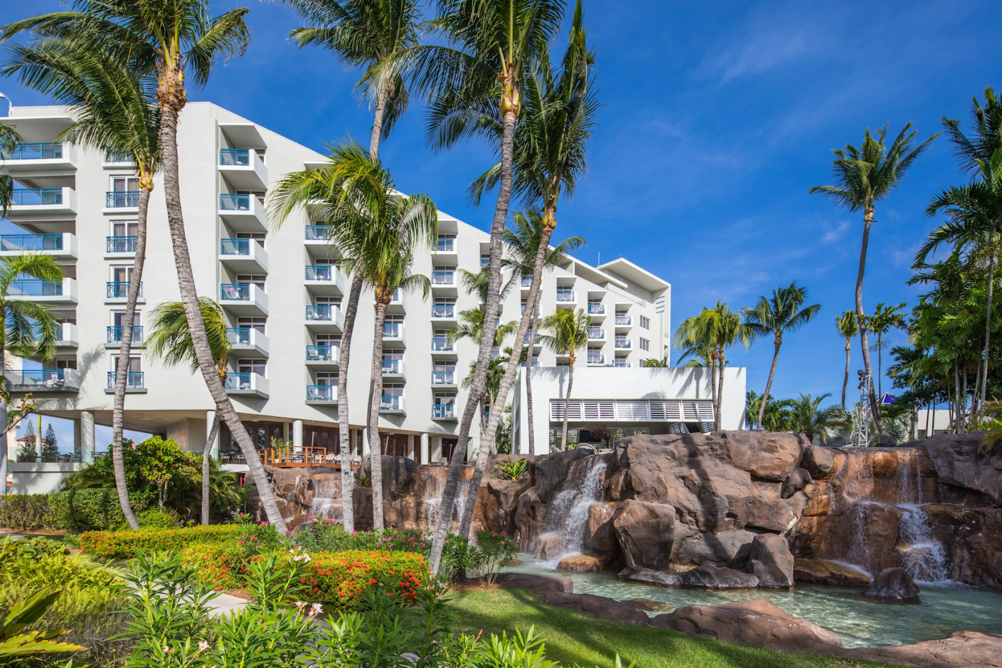 Hilton Aruba Caribbean Resort & Casino, one of the best resorts in Aruba, surrounded by palm trees, cascading rock waterfalls, and lush tropical gardens on Palm Beach.”