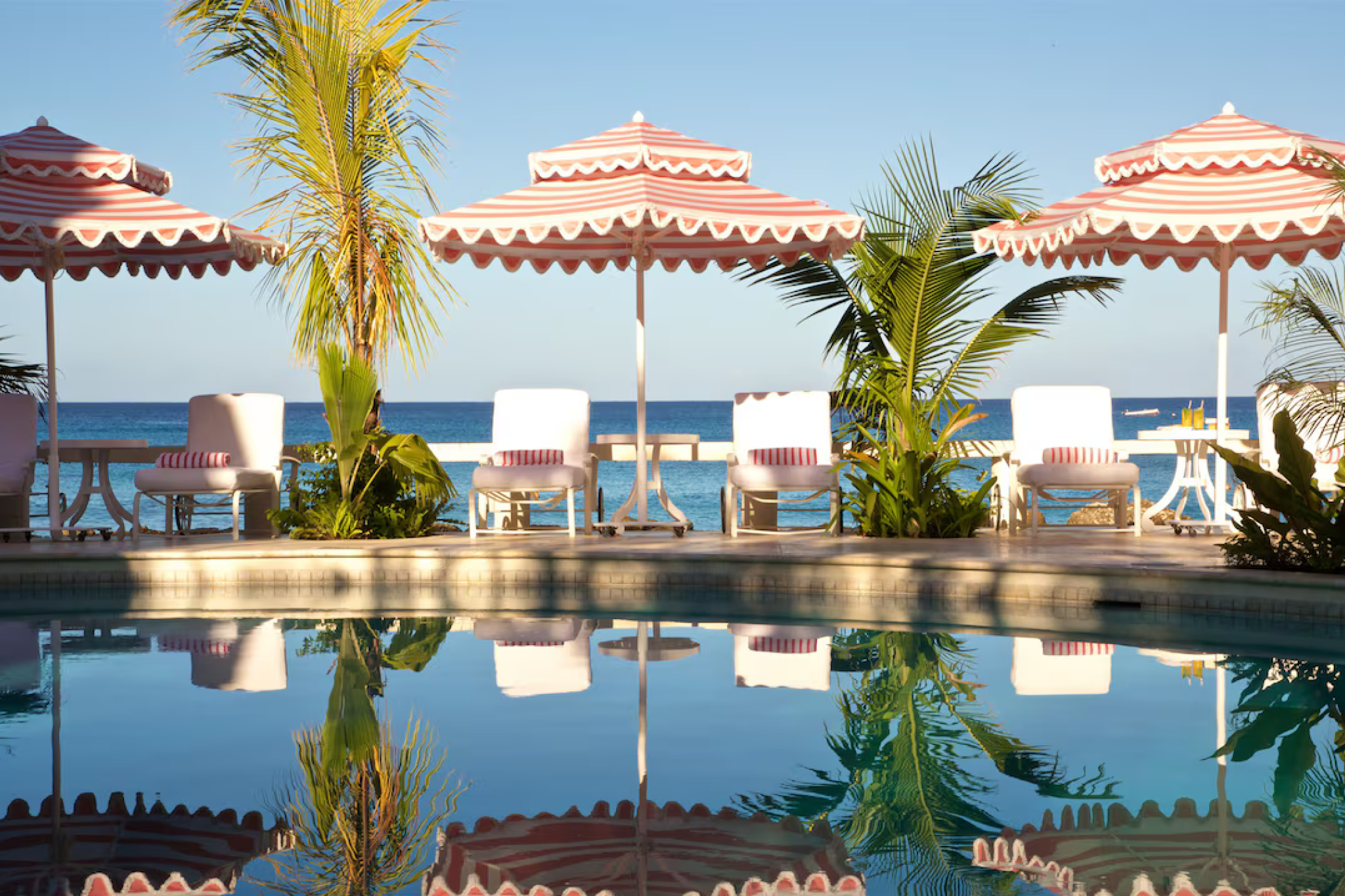 Striped umbrellas and poolside charm at Cobblers Cove, a boutique hotel blending English elegance with Caribbean beauty, one of the best luxury resorts in Barbados.