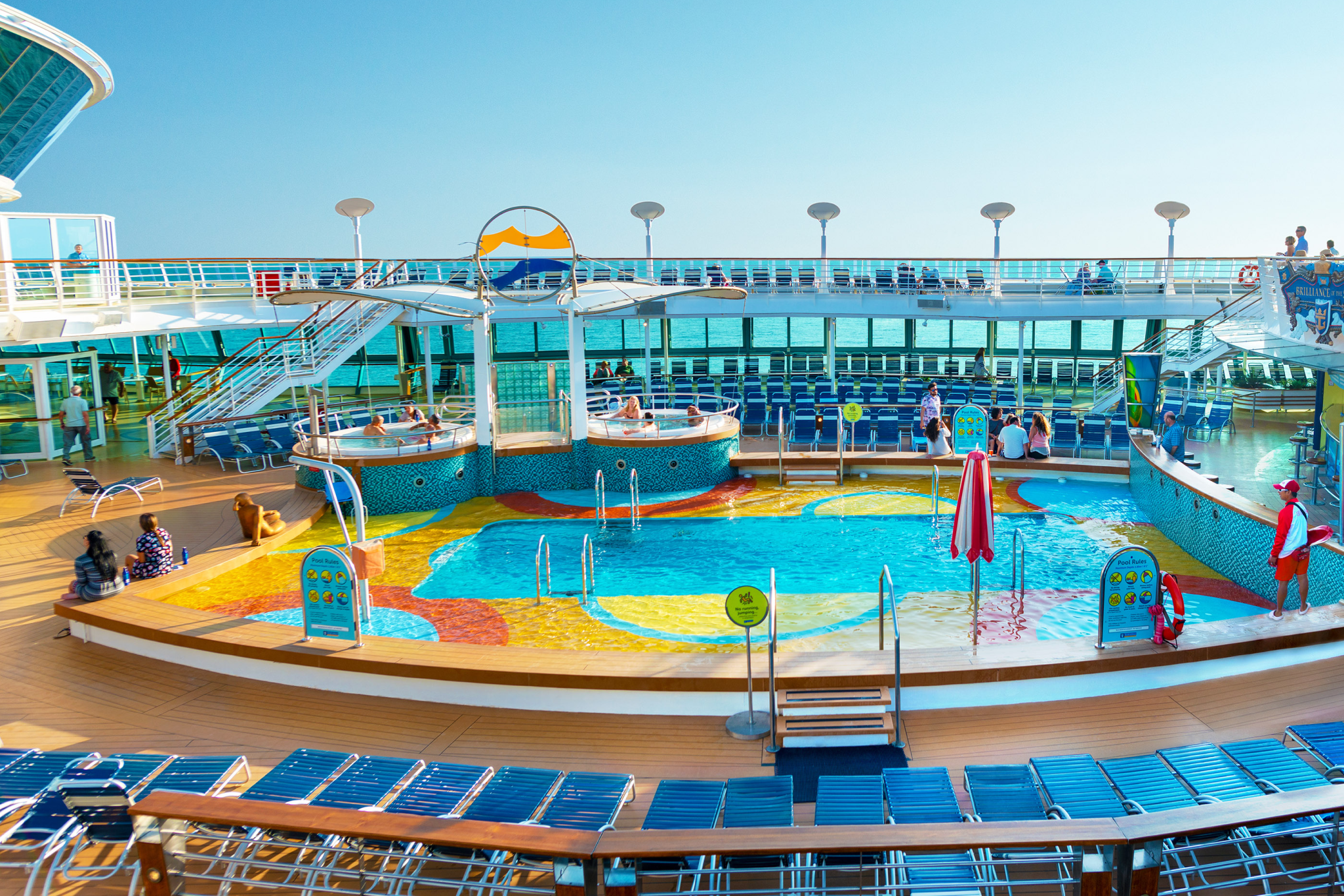 Colorful main pool area on Brilliance of the Seas with loungers, hot tubs, and family-friendly water features.