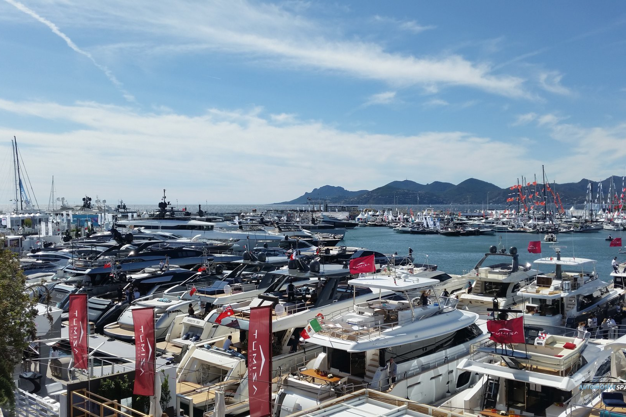 A panoramic view of luxury yachts docked at Vieux Port during the Cannes Yachting Festival 2025, with the Lérins Islands and Esterel mountains in the background.