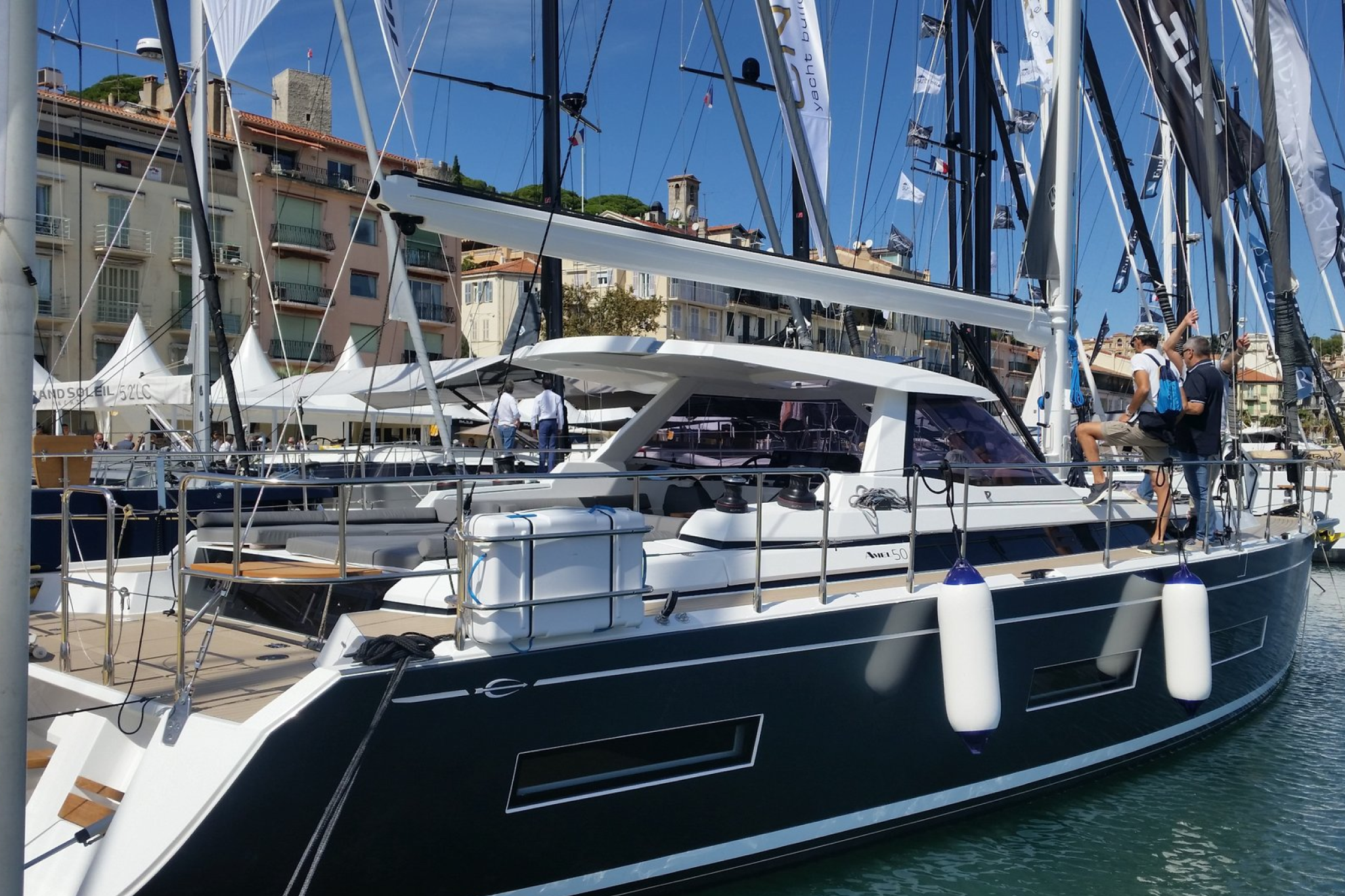 A modern sailing yacht on display at Port Canto during the Cannes Yachting Festival 2025, with visitors touring the deck under a clear blue sky.