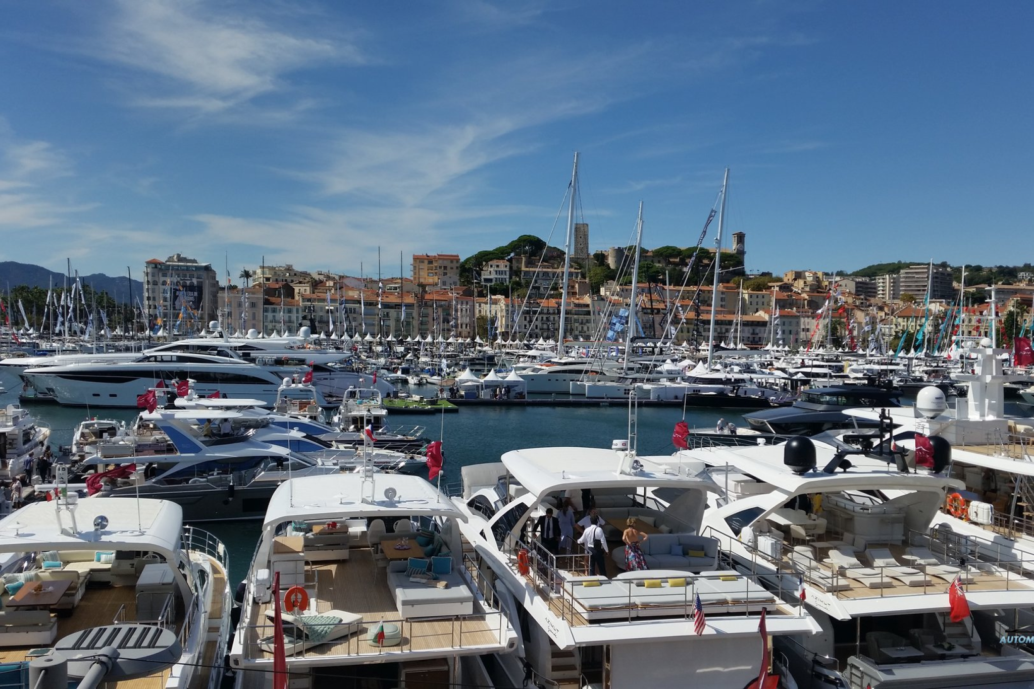 Crowds and rows of yachts fill the marina at the Cannes Yachting Festival 2025, set against the historic skyline of Cannes and its waterfront.