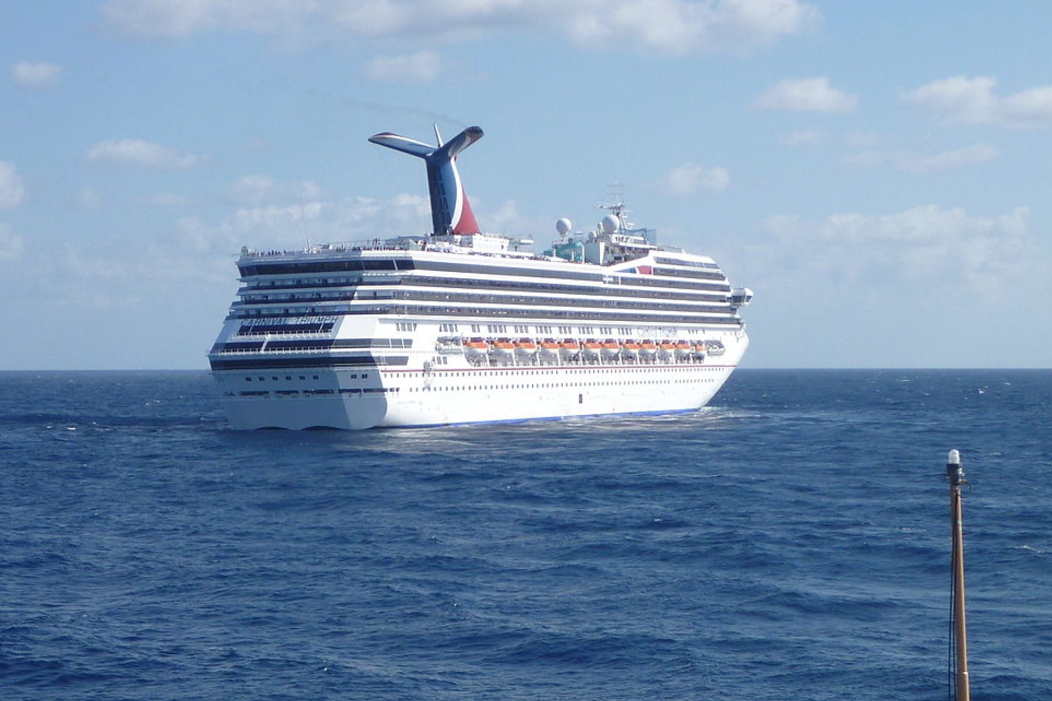 Carnival Cruise Lines Ships by Size image showing Carnival Sunrise sailing in daylight, with its streamlined hull, renovated deck layout, and visible outdoor recreation spaces